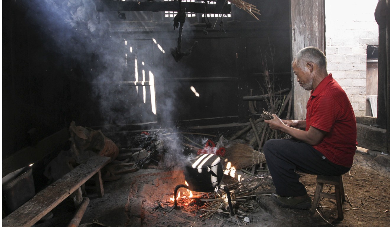 A man burns wood to boil water at his home in Guizhou’s Yuping county in July. Photo: Simon Song