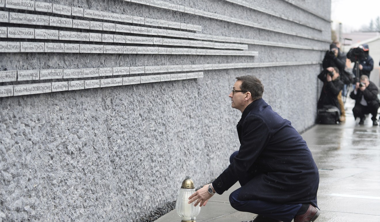 Polish Prime Minister Mateusz Morawiecki places a candle at the Holocaust memorial wall in Markowa. Photo: AP