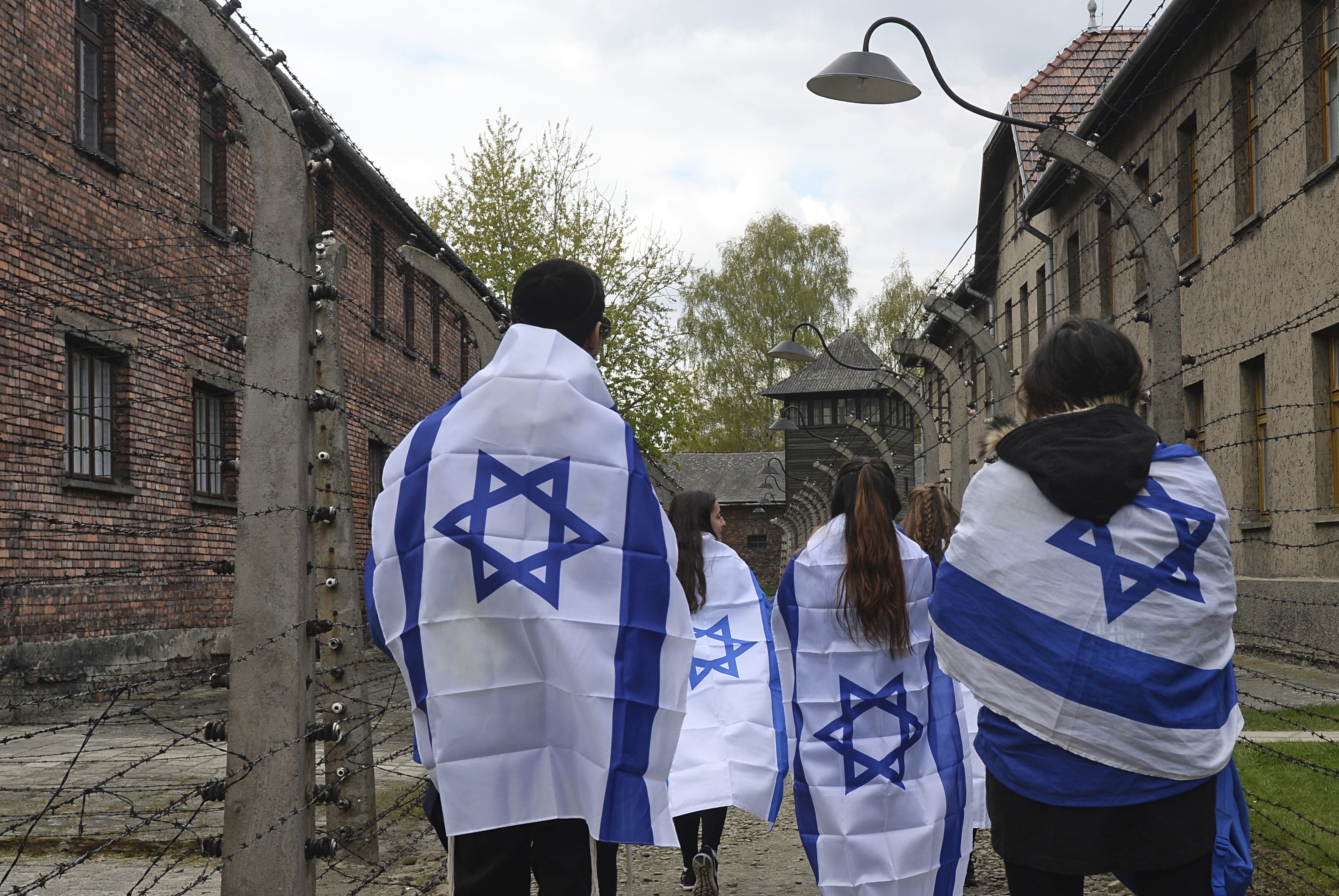 Participants in the yearly March of the Living walk between barbed wire fences in the former Nazi death camp of Auschwitz-Birkenau in Poland, on April 24, 2017. Jews from Israel and around the world marched the route from Auschwitz to Birkenau to commemorate Holocaust victims. A law recently passed by the Polish legislature would make it a crime to refer to such camps as “Polish”. Photo: AP