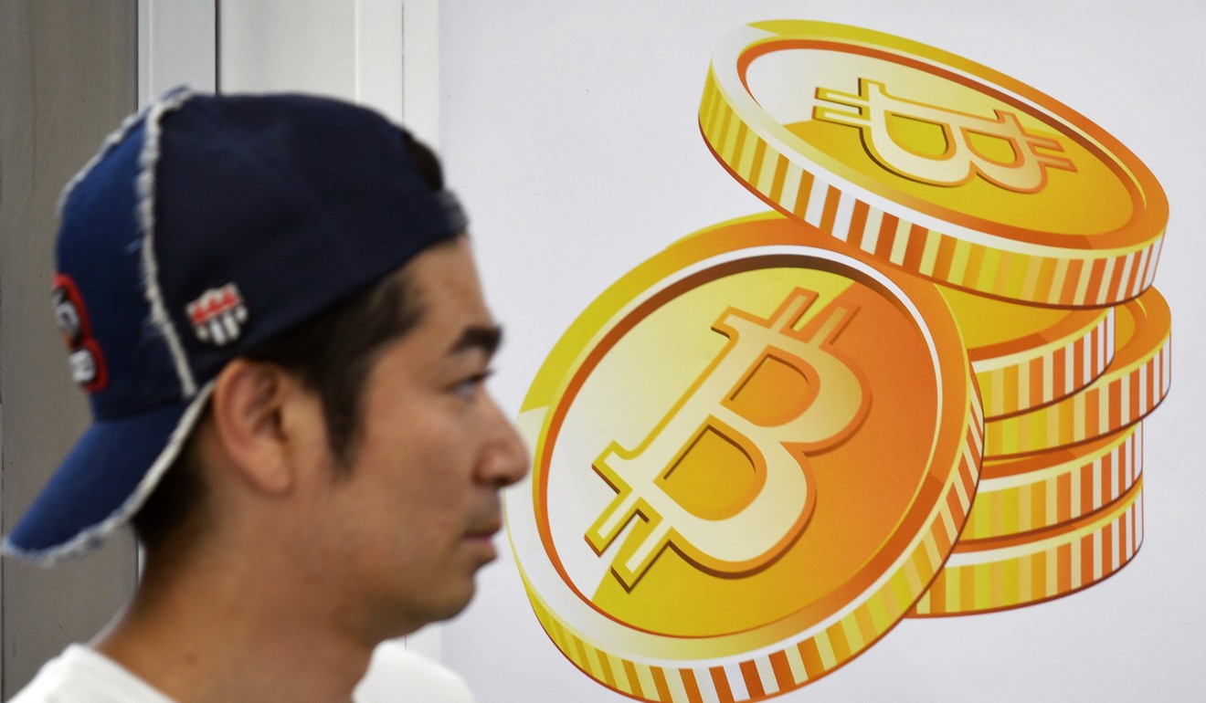 A pedestrian walks past a bitcoin currency poster at the entrance of an electronics retailers store in Tokyo. Photo: EPA