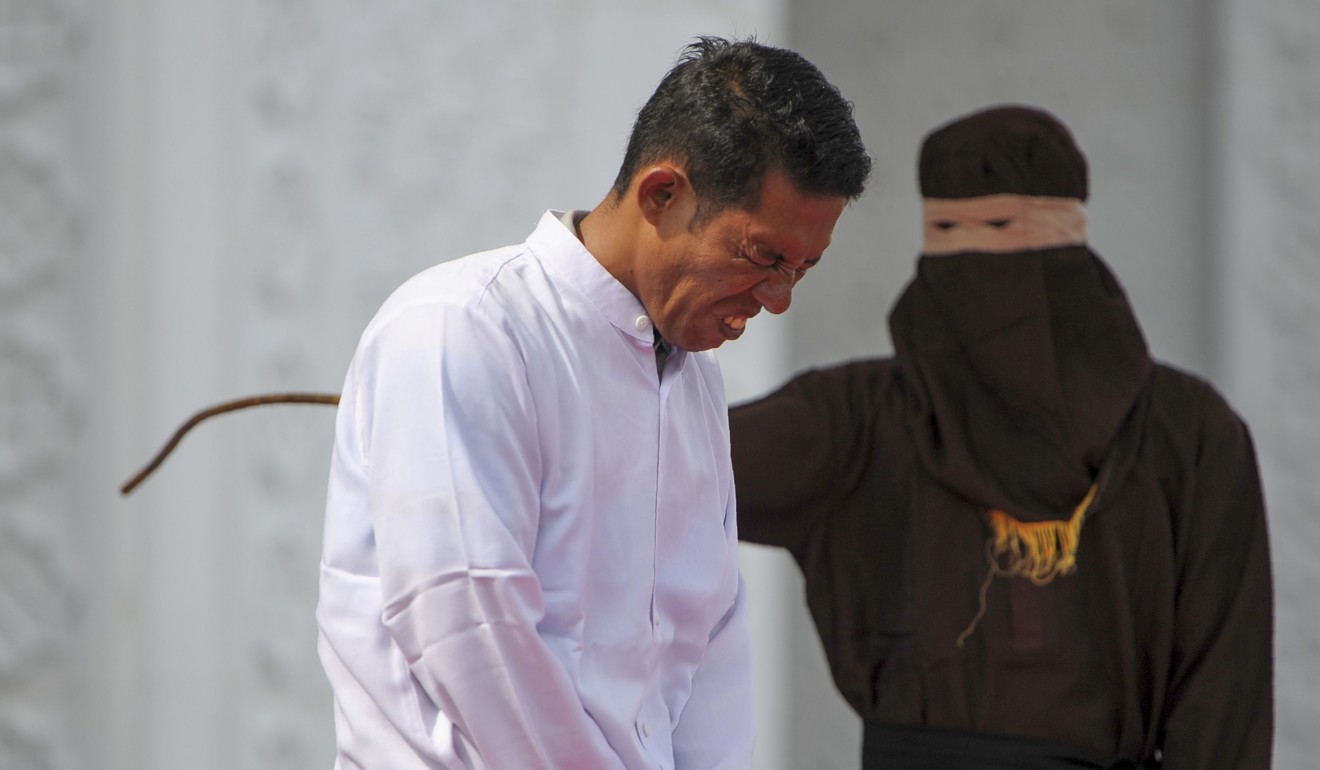 An Indonesian Christian grimaces in pain as he is flogged for selling alcohol, in front of a crowd outside a mosque in Banda Aceh, Aceh province, Indonesia, on January 19. Photo: AFP