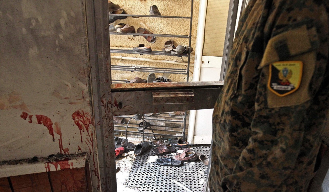 A Libyan wearing military fatigue inspects the interior of the mosque in Benghazi on Friday after it was hit by two bombs – one in a shoe storage area and one in a coffin. Photo: AFP