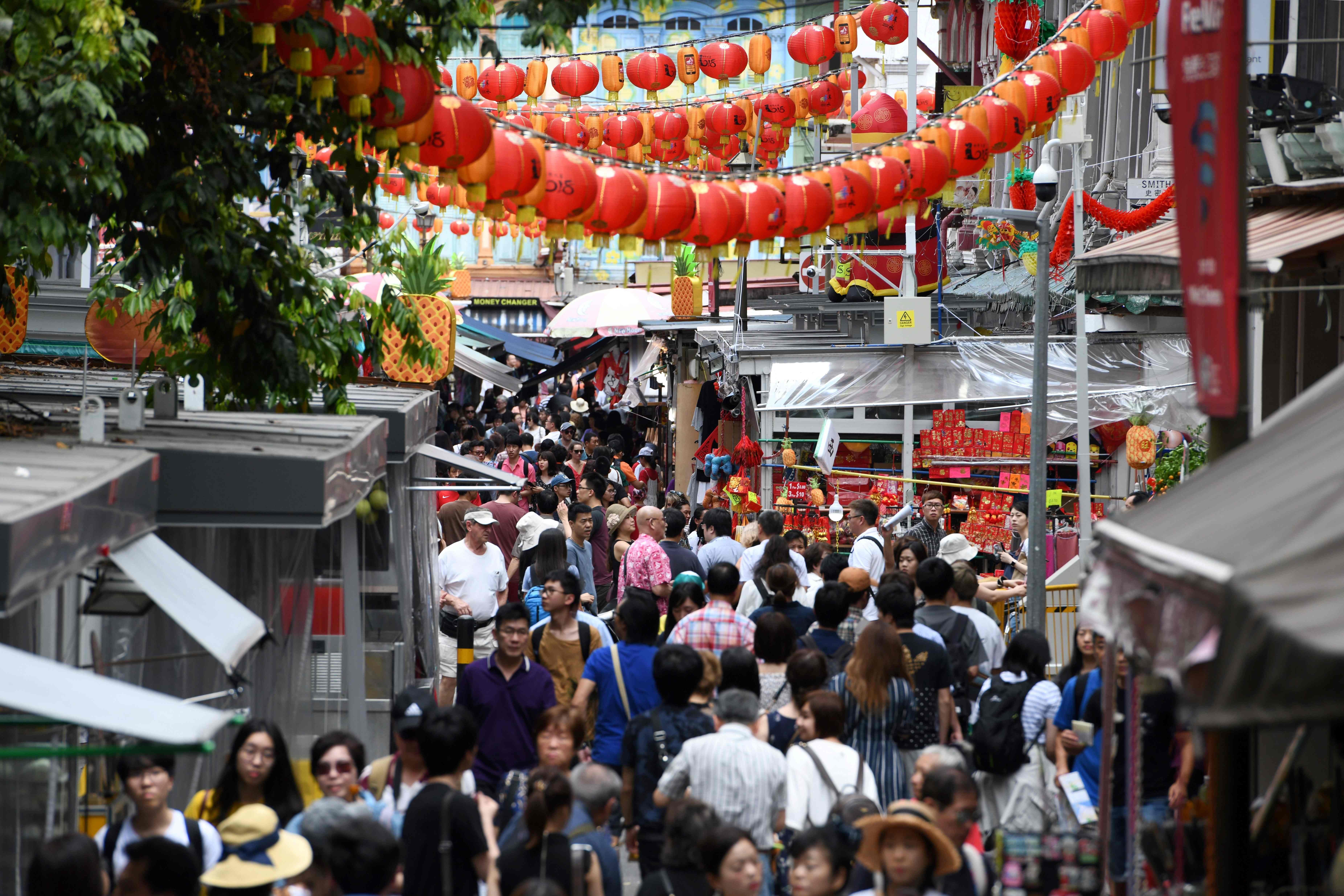 People walk along a crowded alleyway past stalls selling gifts and decorative items in the Chinatown district in Singapore. Photo: AFP