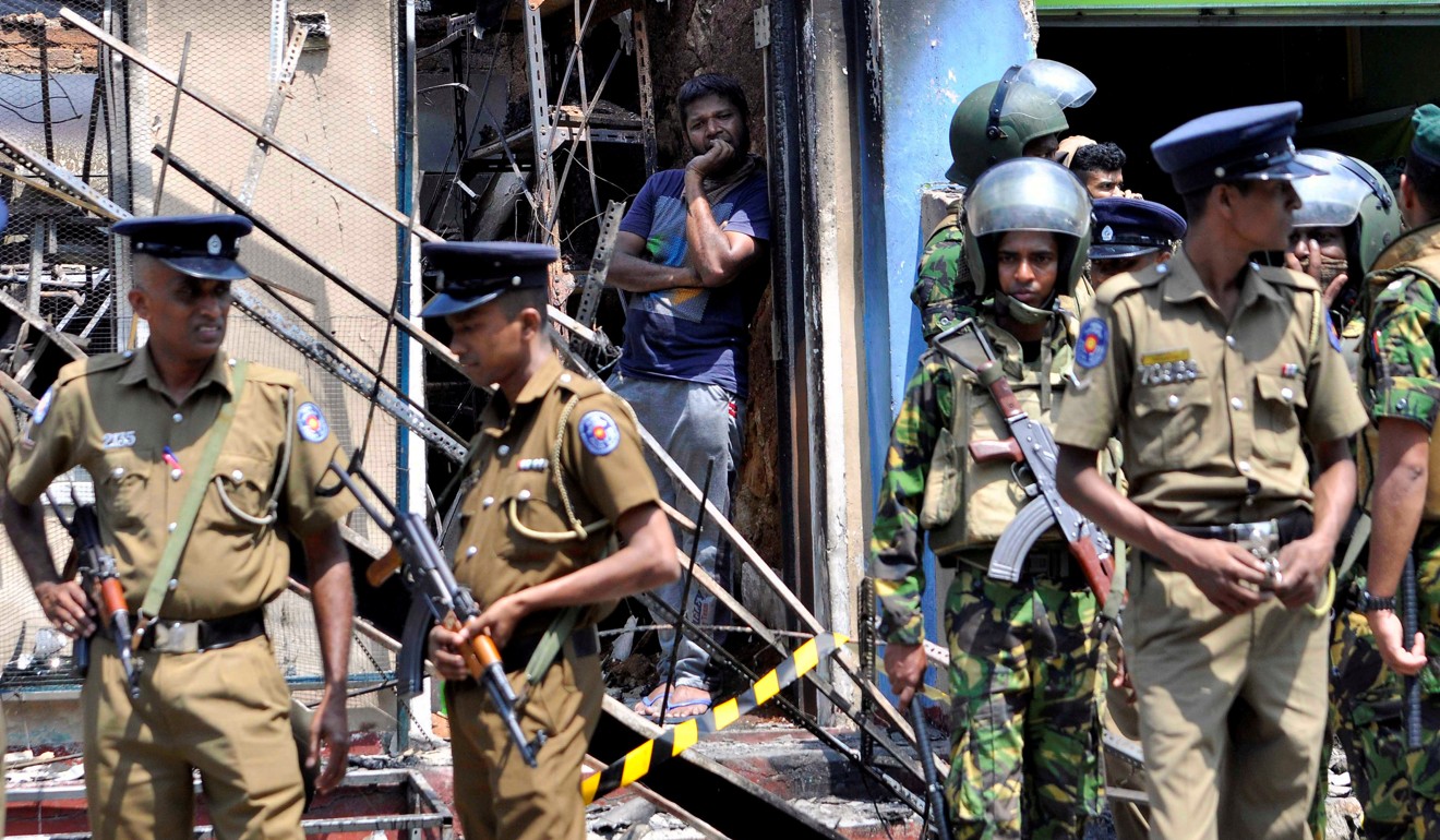 Sri Lankan police stand guard near a burnt house after a clash between two communities in Digana. Photo: Reuters