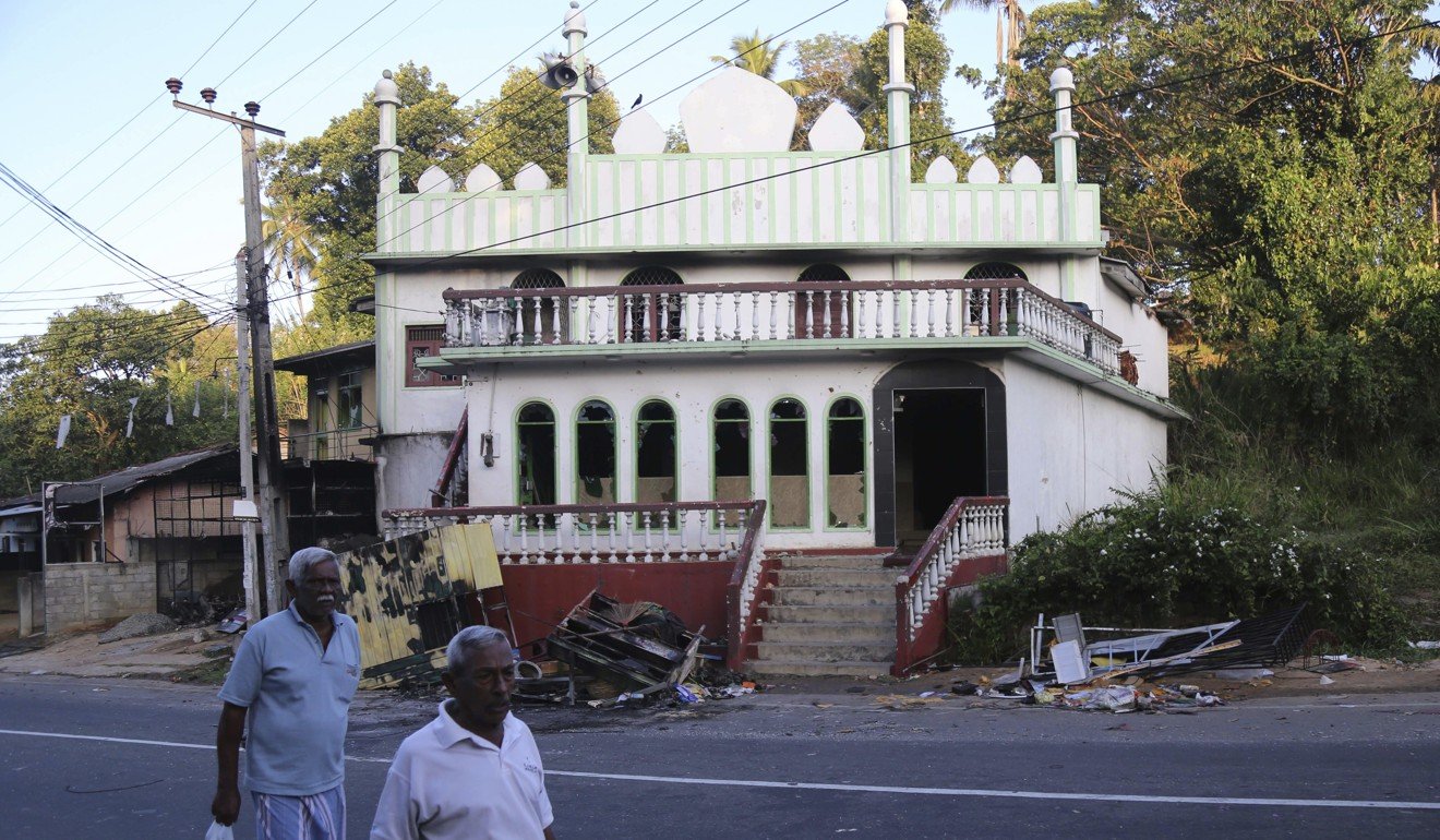 Sri Lankans walk past a vandalised Mosque in Digana, Sri Lanka. The president declared a state of emergency on Tuesday amid fears that anti-Muslim attacks in several central hill towns could spread. Photo: AP