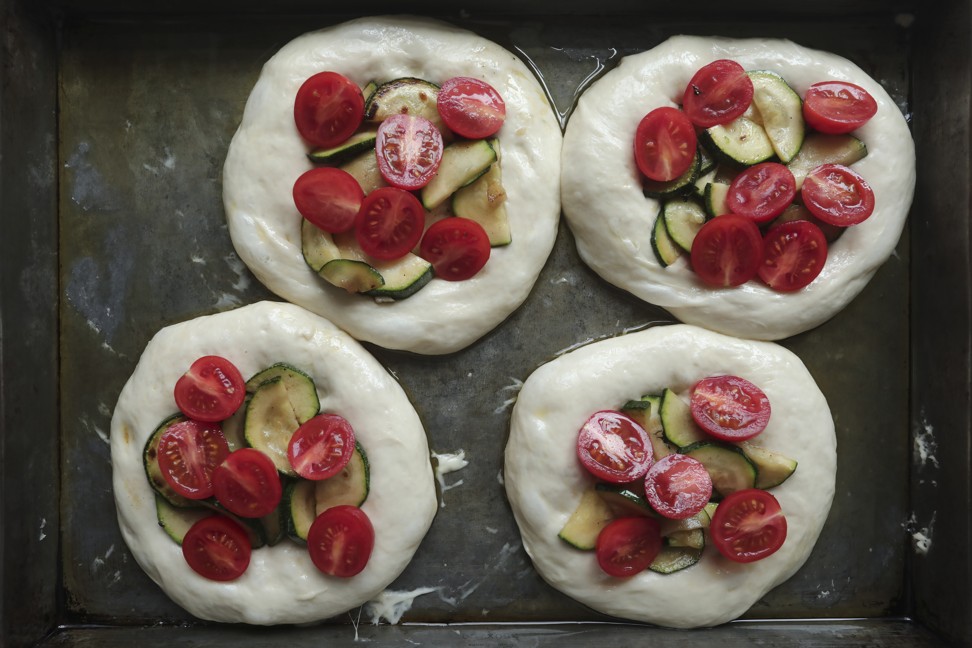 The dough topped with zucchini and cherry tomatoes.