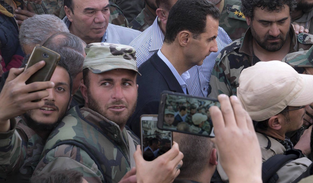 Syrian soldiers take selfies with Syrian President Bashar al-Assad, centre, as he visits his troops at the front line in the newly captured areas of eastern Ghouta, near the capital of Damascus on March 18, 2018. Photo: Syrian presidency Facebook page via AP
