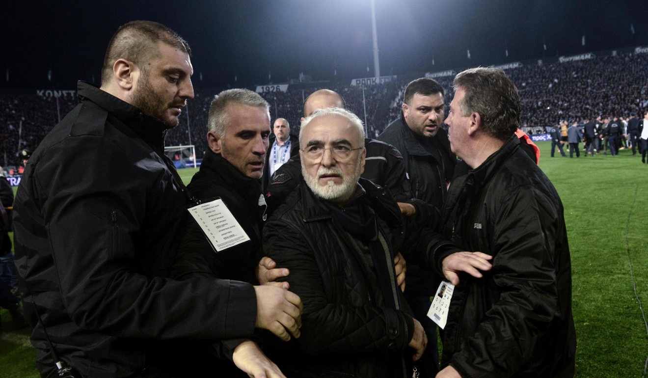 PAOK owner Ivan Savvidis (centre) is escorted away after taking to the pitch carrying a handgun in his waistband during a March 11 Greek Superleague football match in Thessaloniki. Photo: Agence France-Presse