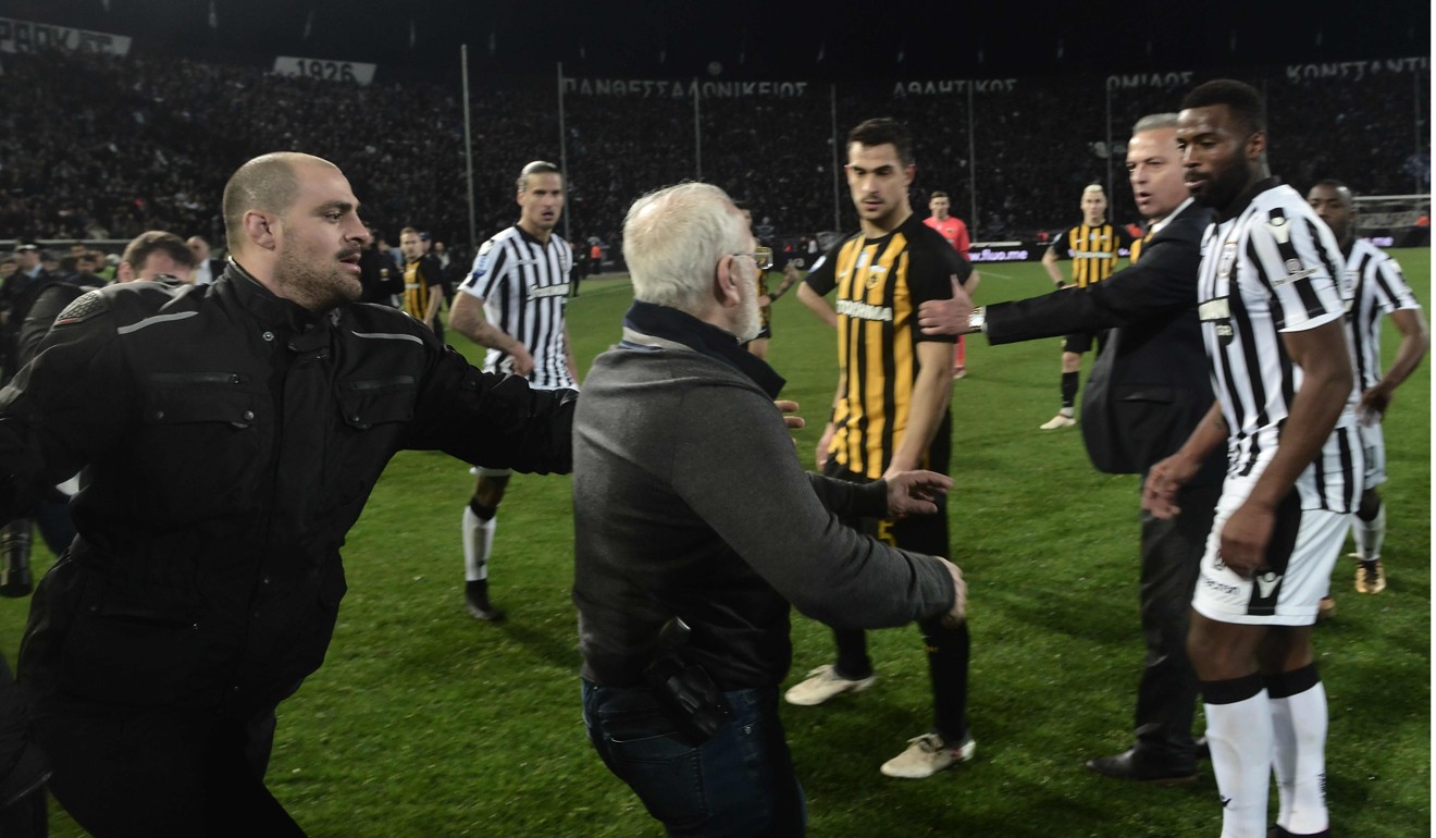 PAOK owner Ivan Savvidis, centre, wears a gun on his hip as he lunges at AEK Athens' operations manager Vassilis Dimitriadis, centre, while his bodyguard and PAOK players try to stop him during a Greek League soccer match in the northern Greek city of Thessaloniki on March 11. Photo: Agence France-Presse
