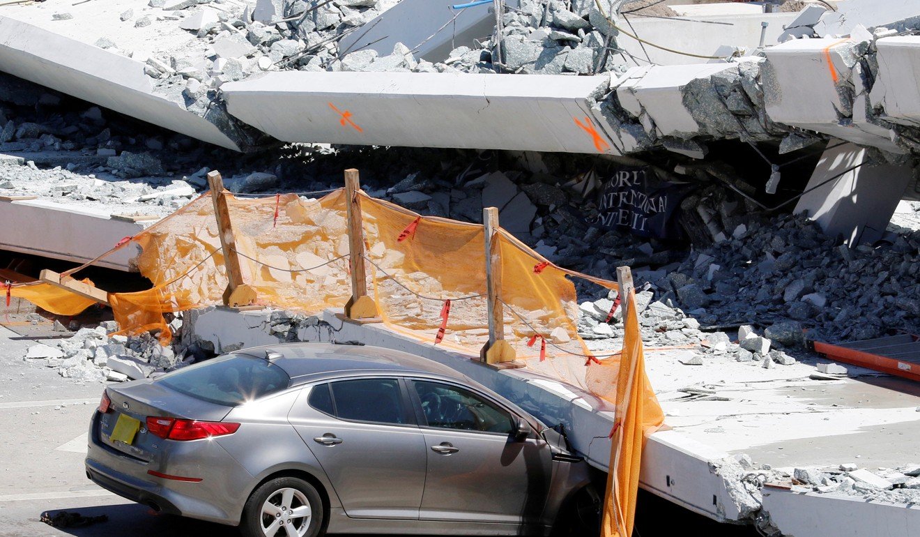 A damaged car is seen partially trapped as workers remove debris from a collapsed pedestrian bridge at Florida International University in Miami, Florida, on March 16, 2018. A survivor has filed a lawsuit against the companies who built the bridge. Photo: Reuters