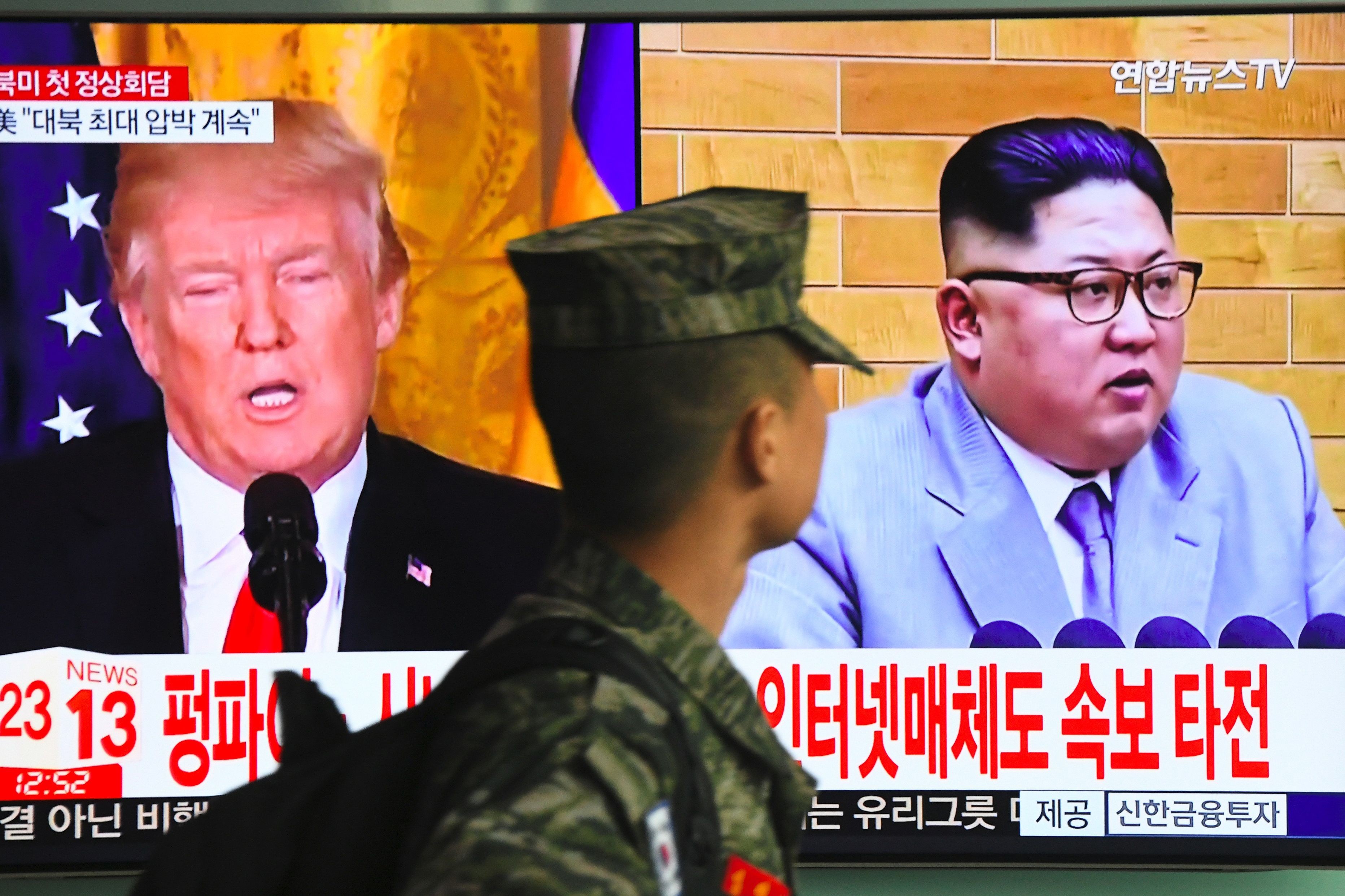 A South Korean soldier walks past a television screen showing pictures of US President Donald Trump (left) and North Korean leader Kim Jong-un at a railway station in Seoul on March 9. Trump agreed on March 8 to a historic first meeting with Kim. Photo: AFP  