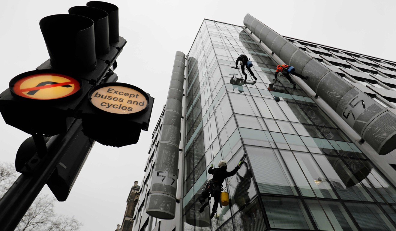 Workers clean the windows of the shared building which houses the offices of Cambridge Analytica in central London on March 24, 2018. British regulators finished searching the offices of Cambridge Analytica, the firm at the centre of a Facebook data scandal, before dawn on Saturday and said they would examine the evidence before considering “next steps”. Photo: AFP