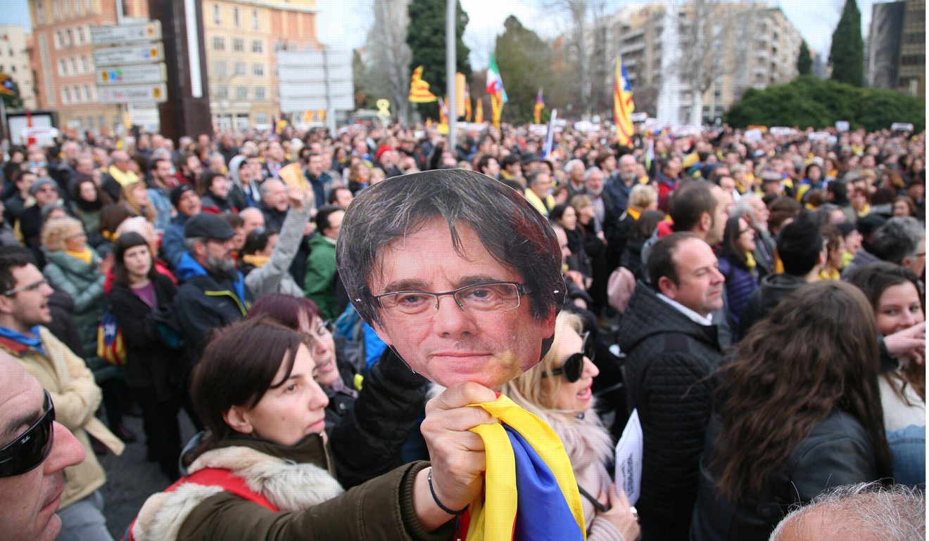 Protesters hold cardboard masks with the face of former Catalan leader Carles Puigdemont during a protest against his arrest in Tarragona, north eastern Spain, on Sunday. Photo: EPA