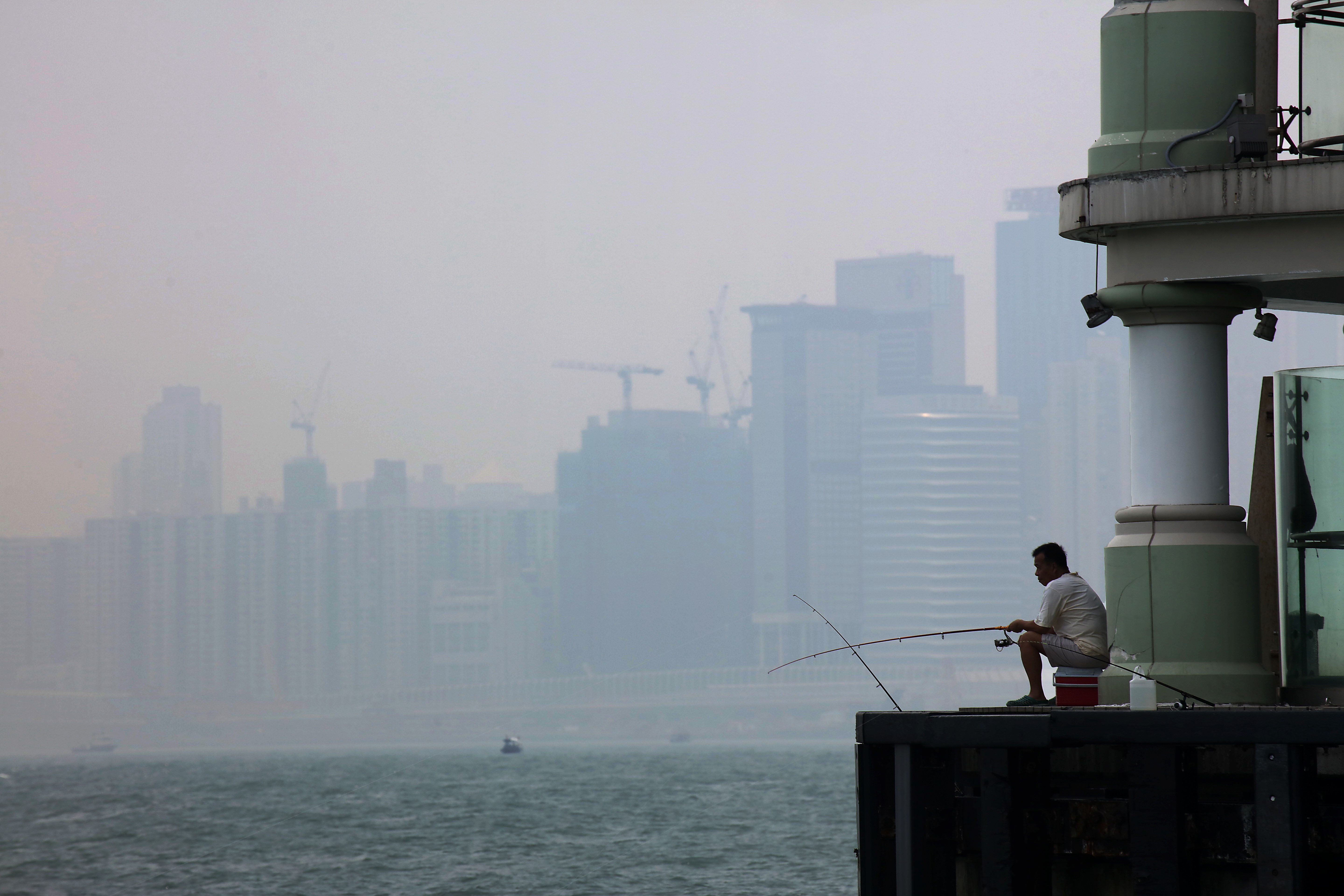 A local resident fishes at Victoria Harbour in July 2017, on a day when Hong Kong recorded “very high” to “serious” levels of air pollution across the city. Photo: Felix Wong