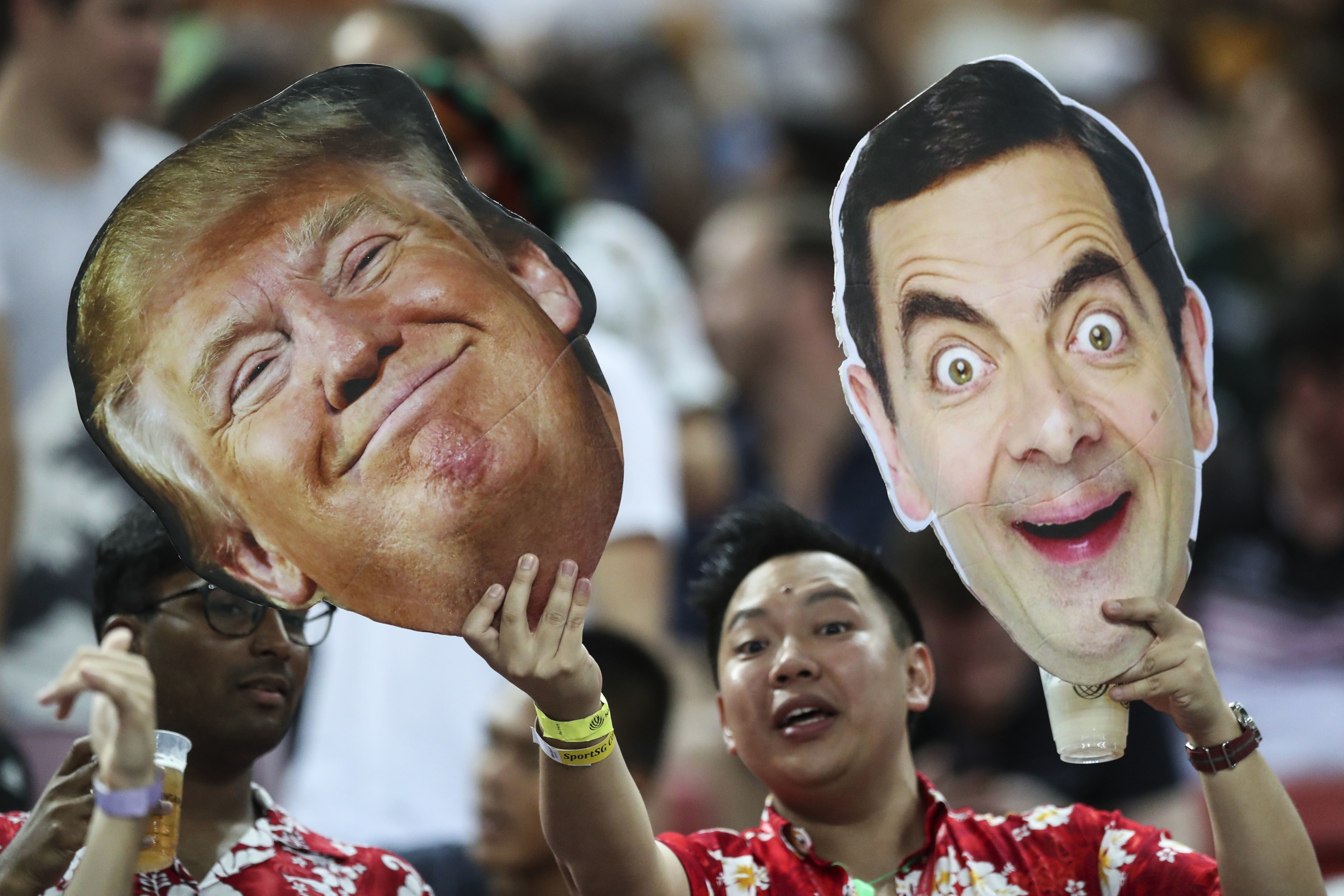 A fan holds up cutouts of US President Donald Trump and Mr Bean, played by British actor Rowan Atkinson, during the HSBC World Rugby Sevens Series 2018 finals on April 29 in Singapore. Trump’s “madman” diplomacy might just secure him enough foreign policy wins to shore up his reputation at home. Photo: AP 