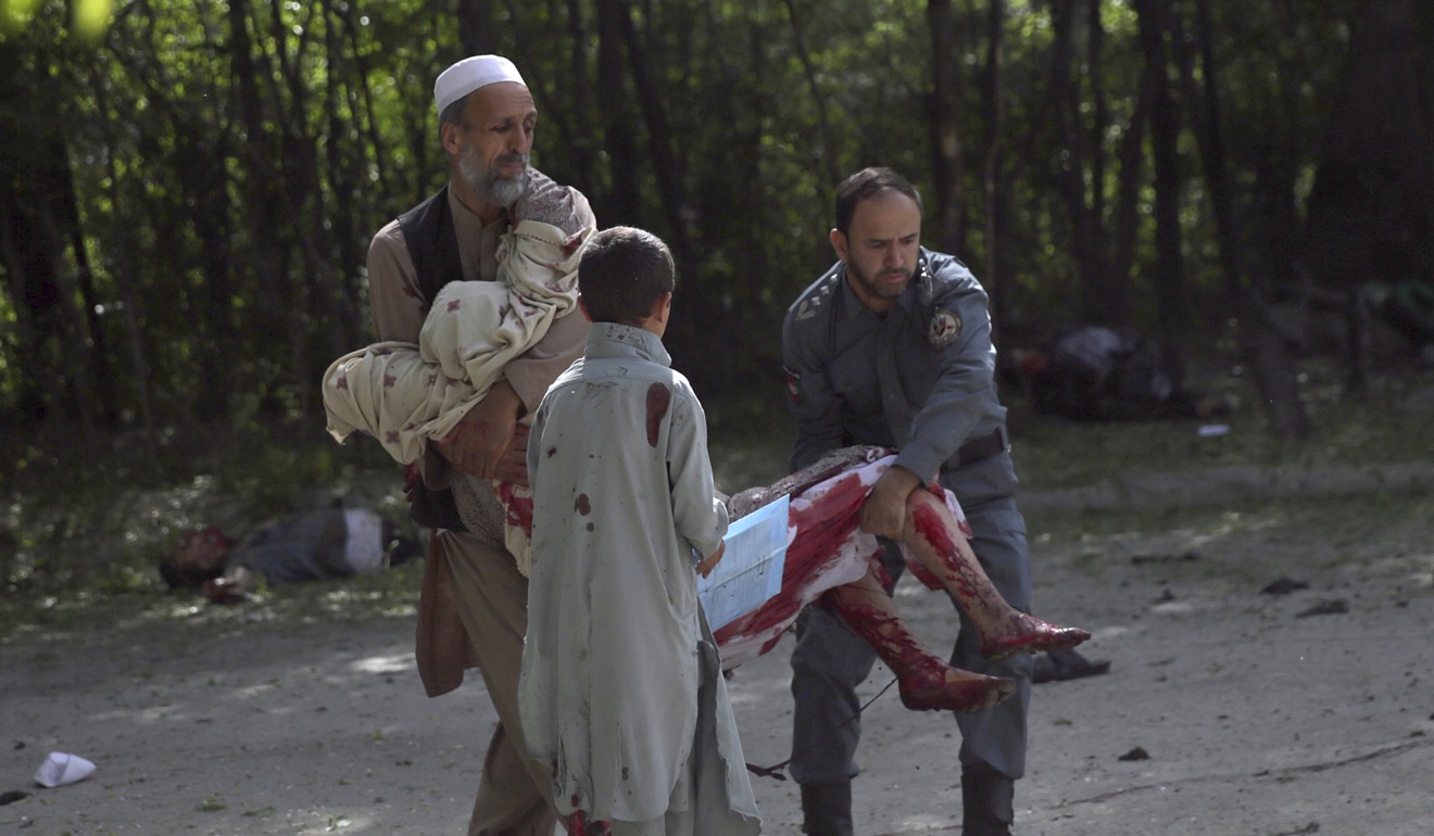 A wounded woman is helped at the site of explosions in Kabul on Monday. Photo: AP