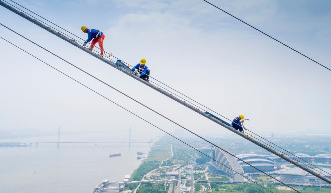 Workers labouring on the construction of a double-deck suspension bridge crossing the Yangtze River in Wuhan, Hubei province. China needs growth to avoid the dreaded middle-income trap. Photo: AFP 