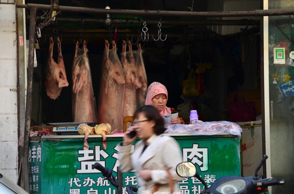 A Hui woman reads as she waits for customers at a halal butcher shop in Yinchuan. Arabic logos for halal food have been replaced with Chinese versions. Photo: Nectar Gan