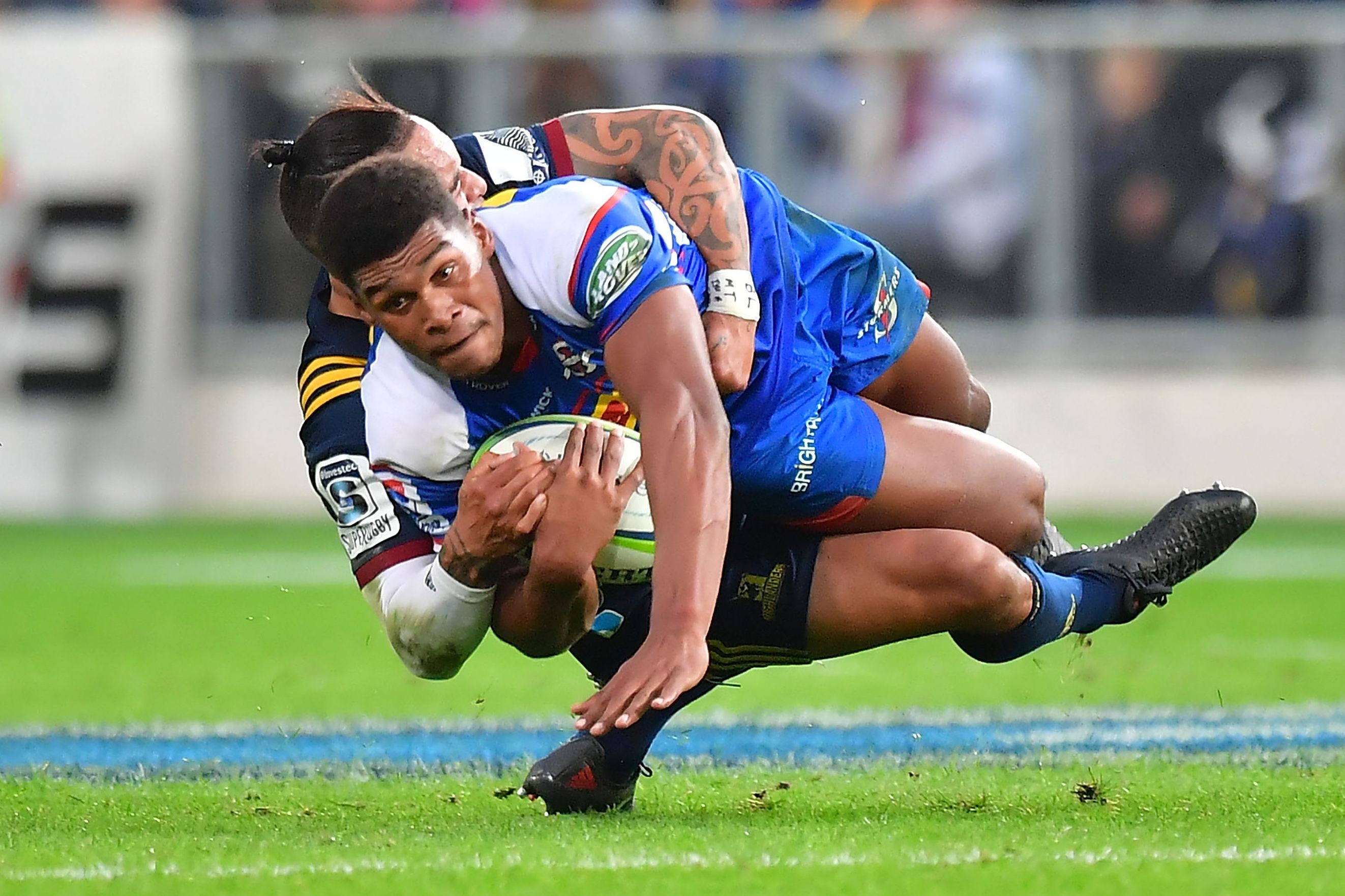 Stormers’ star Damian Willemse is tackled by Highlanders’ scrum half Aaron Smith. Photo: AFP