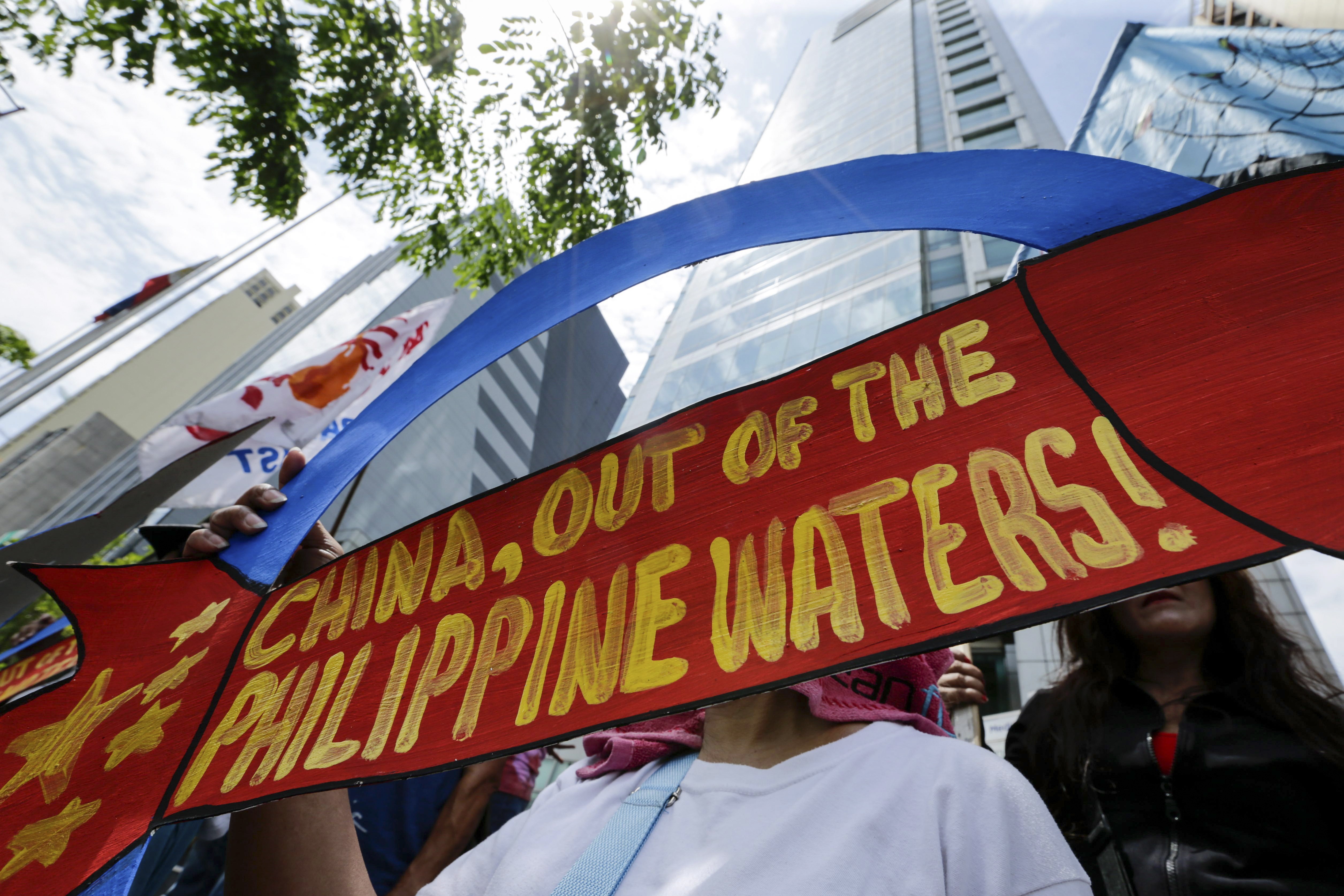 A woman holds a placard at the Chinese consulate in Makati on May 18 in a protest over Beijing’s installation of cruise and surface-to-air missiles on artificial islands in the Spratly group. Photo: EPA-EFE