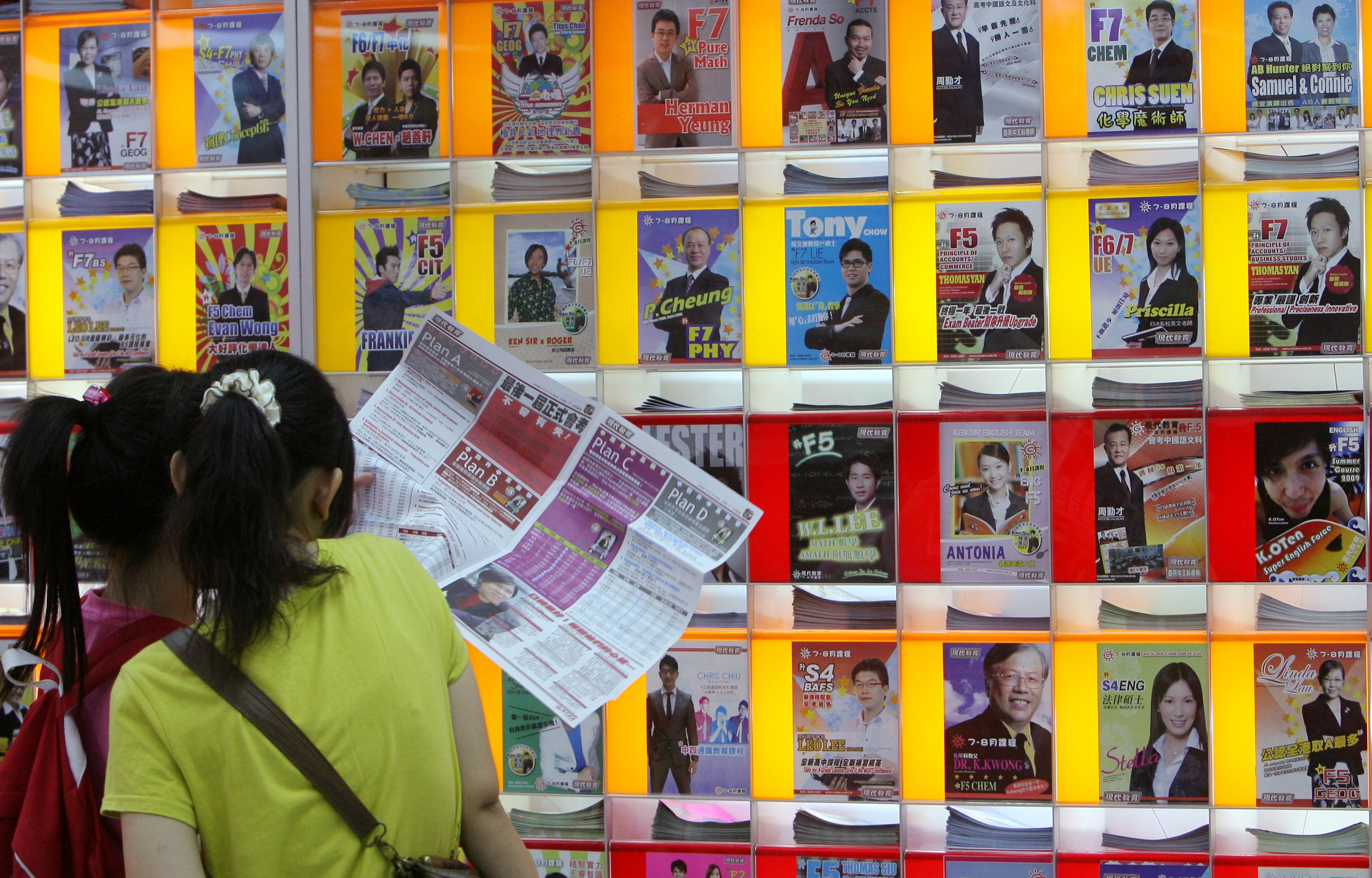 Students stand in front of a wall of adverts for private tutors. Photo: K. Y. Cheng