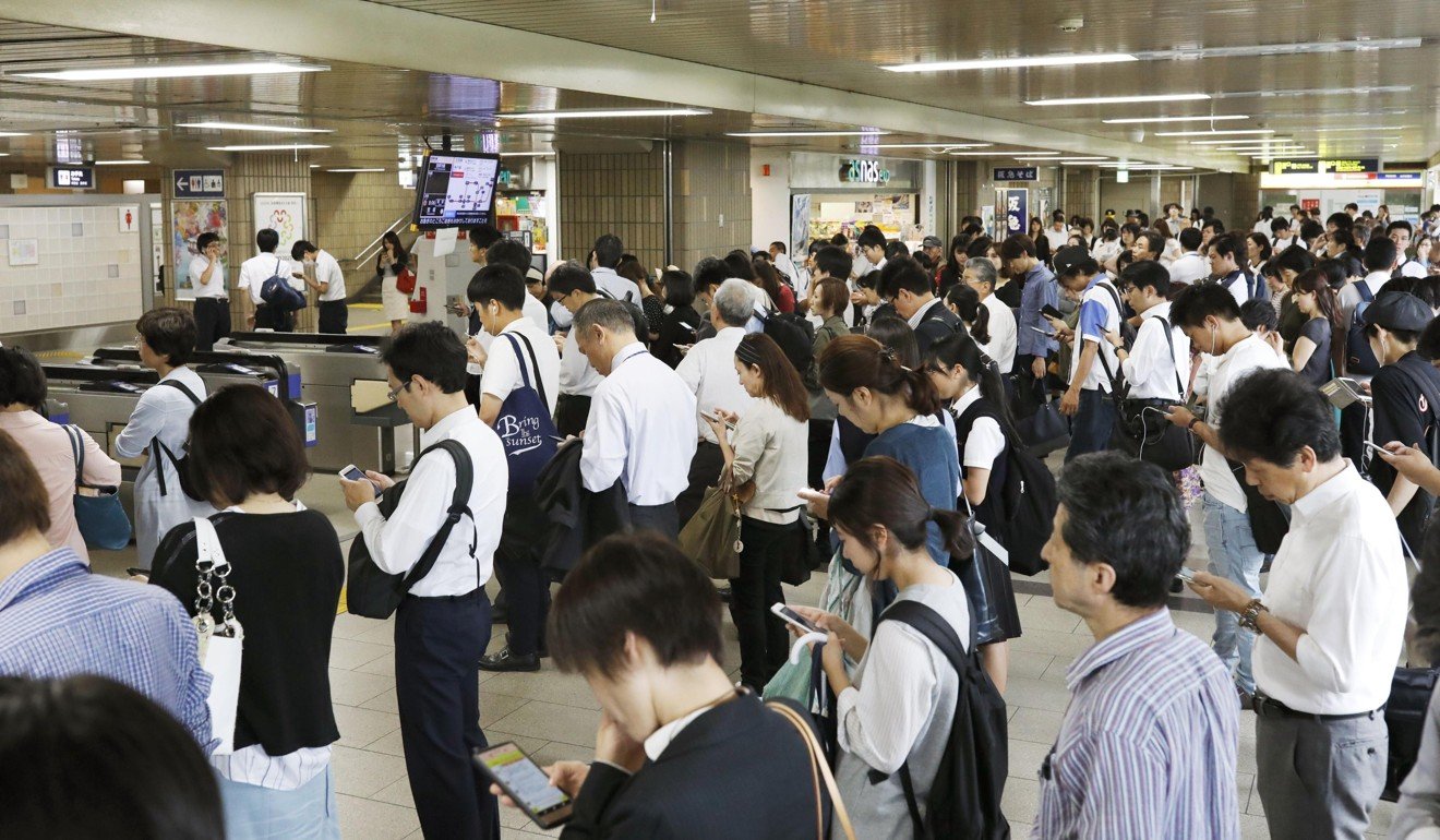 Stranded commuters wait for news in front of a ticket gate at Hankyu Ikeda Station in Osaka. Photo: Kyodo