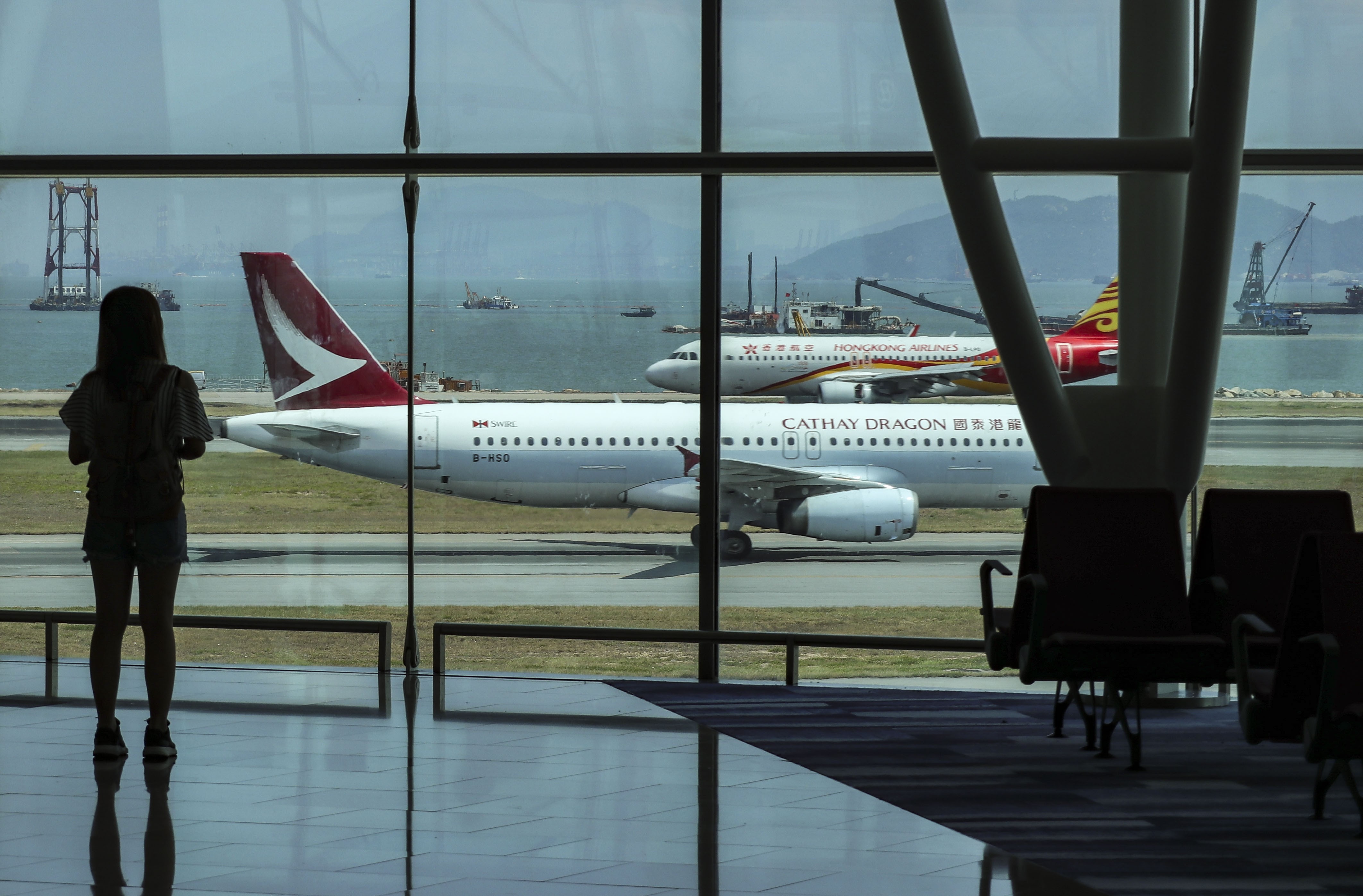 A passenger looks at aircraft at Terminal 2 of the Hong Kong International Airport in Chek Lap Kok on May 27. The city is constructing a third runway to cope with increasing air traffic, and there have been suggestions that it needs a fourth. Photo: Roy Issa