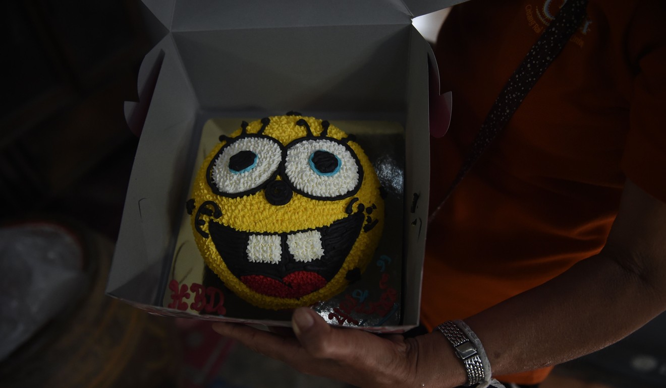 The great aunt of Pheeraphat 'Night' Sompiengjai, one of the members of a Thai youth football team currently trapped at the Tham Luang cave, shows a SpongeBob birthday cake for Night. Photo: AFP