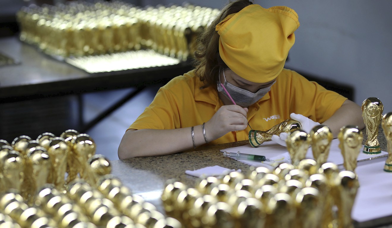 A worker paints Ffia World Cup trophies at a factory in Dongguan in south China’s Guangdong province. Photo: AP