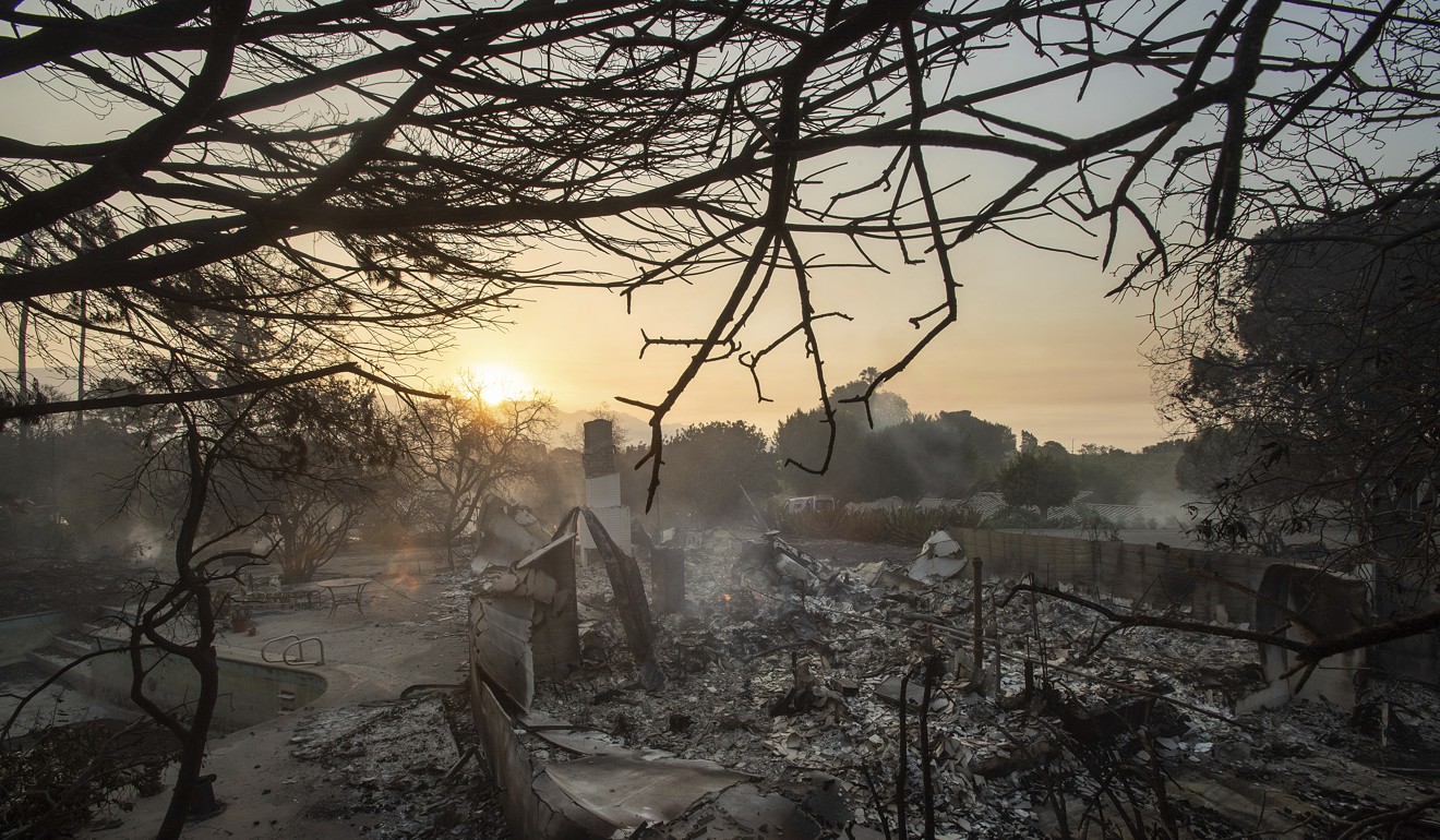 The sun rises behind a home leveled by the Holiday fire in Goleta, California, on Saturday. Photo: AP