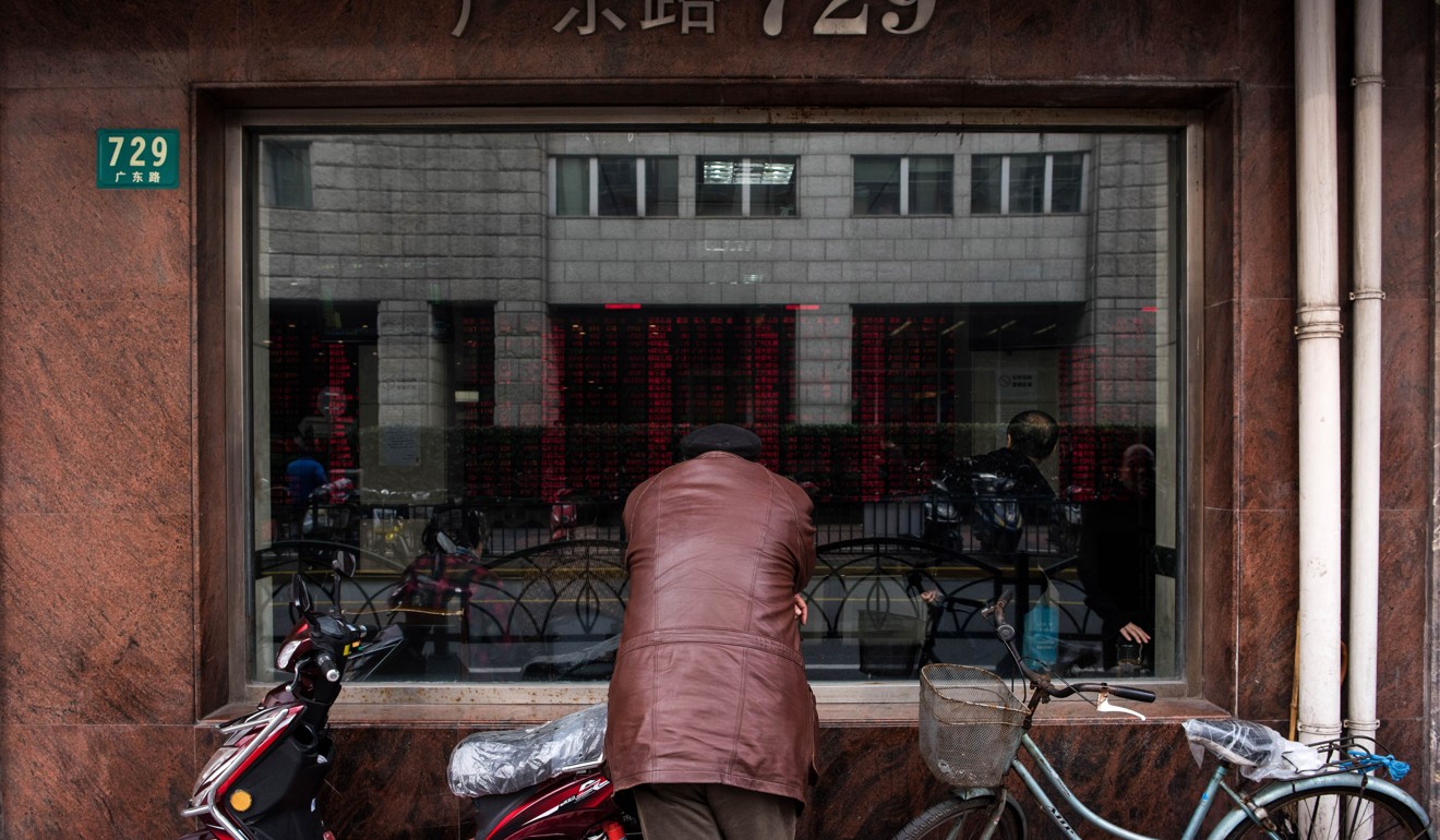 A retail investor looks through a street-front window as he monitors screens showing stock market movements at a brokerage house in Shanghai. Photo: AFP