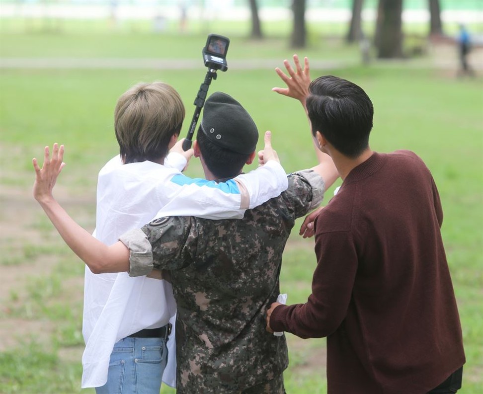 K-pop star Ryeowook (centre) poses for a selfie in front of fans with two other members of boy band Super Junior on Tuesday after completing his military service. Photo: Yonhap