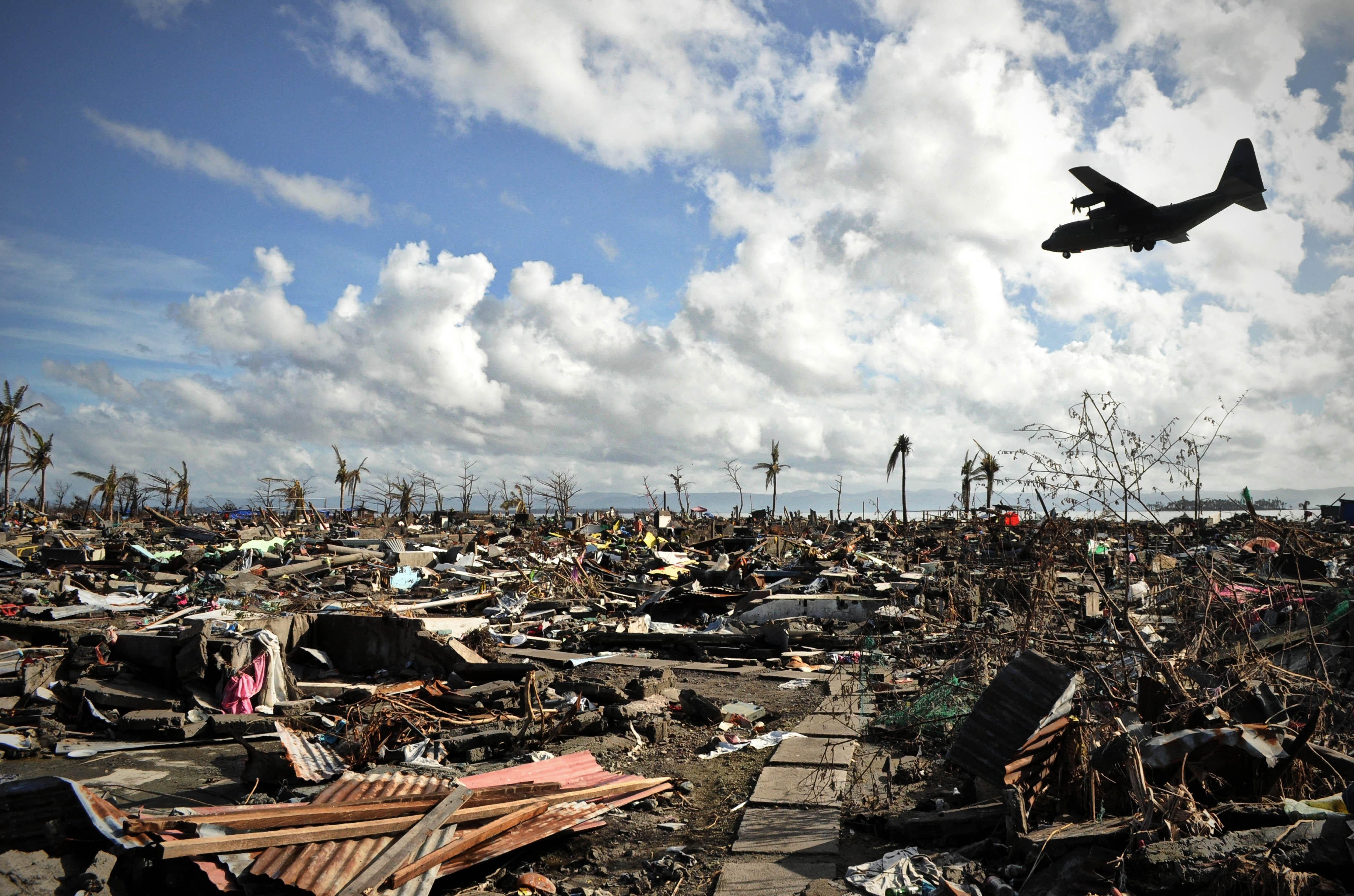 A military aircraft passes over a destroyed area of Tacloban City, the Philippines, after Typhoon Haiyan ripped through it in 2013. Photo: Alamy
