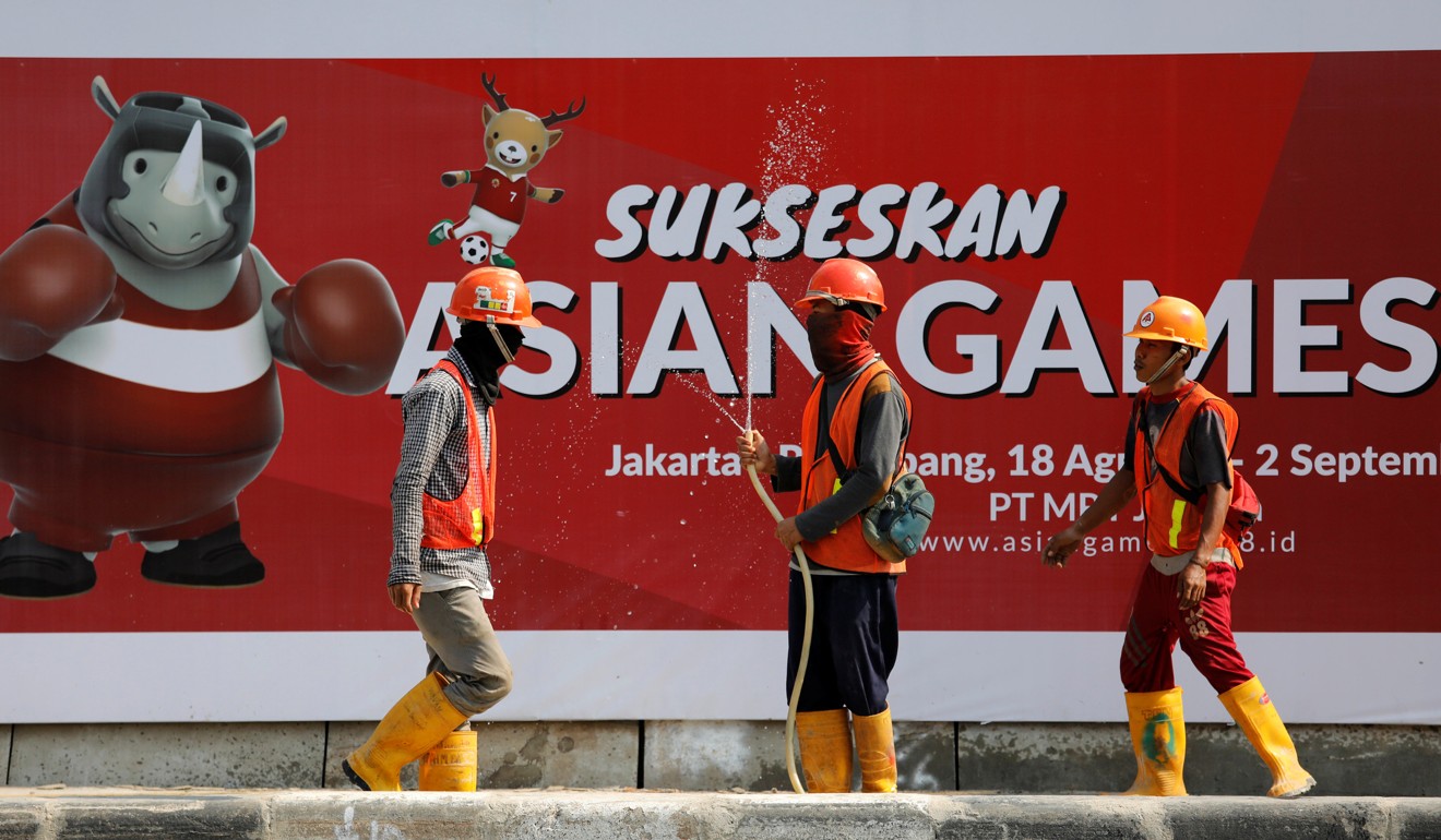 Construction workers near a sign promoting the upcoming 2018 Asian Games. Preparation is said to be ‘99 per cent’ complete. Photo: Reuters