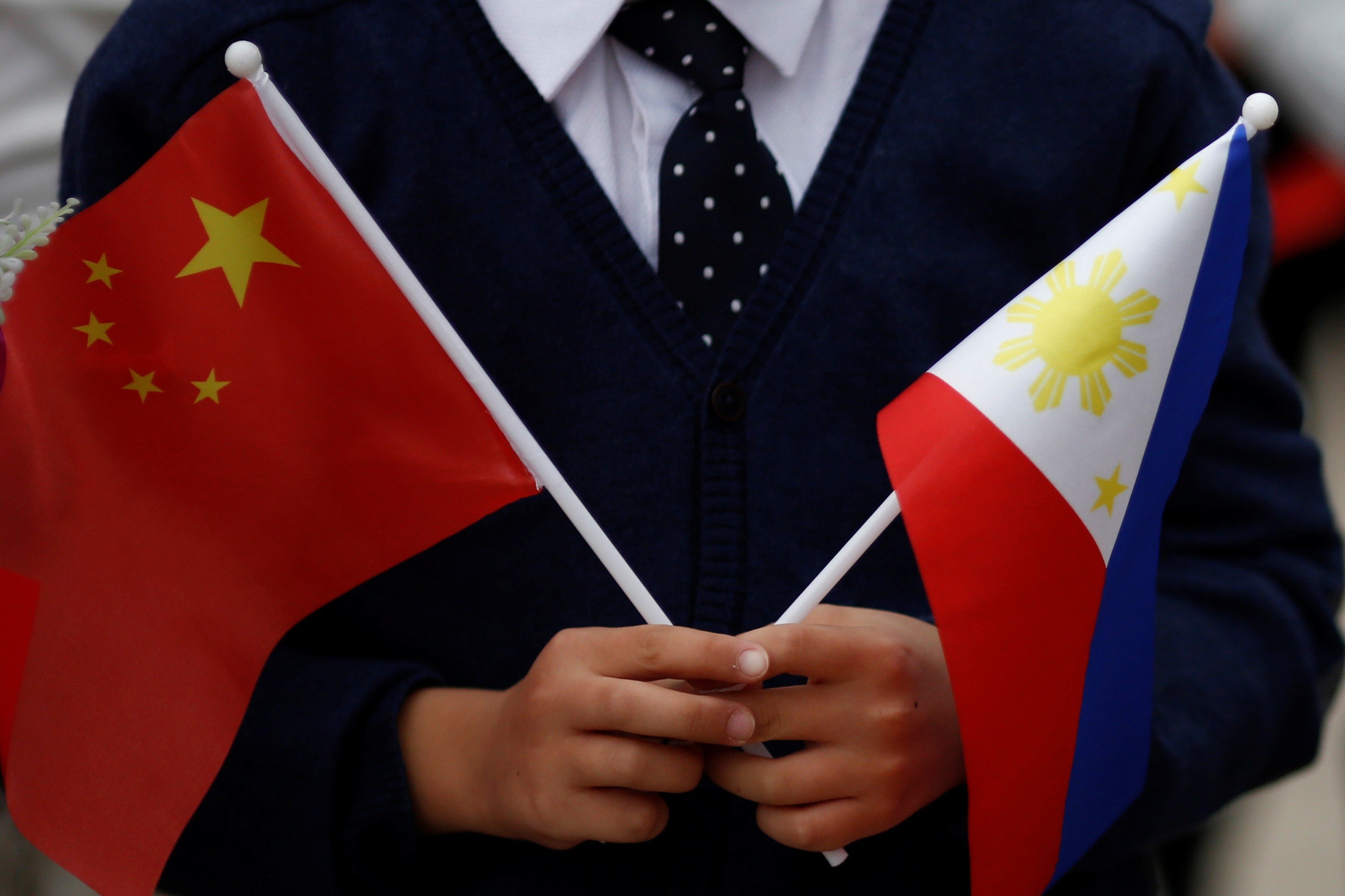 A child holds national flags of China and the Philippines before Philippine President Rodrigo Duterte and China's President Xi Jinping attend a welcoming ceremony in Beijing in October 2016. Photo: Reuters