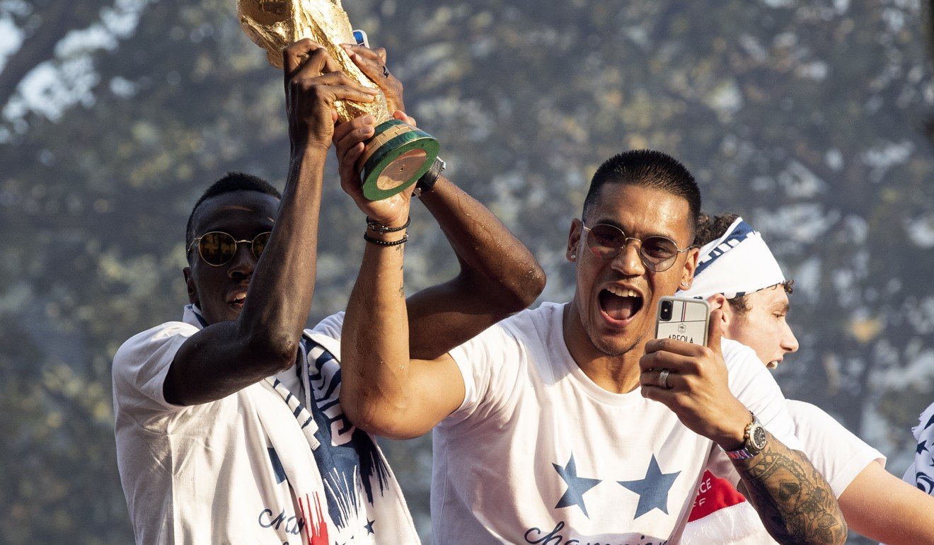 Blaise Matuidi and Alphonse Areola of France lift the World Cup trophy as the France team stand on the rooftop of a bus during a parade down the Champs-Elysee avenue in Paris. Photo: EPA