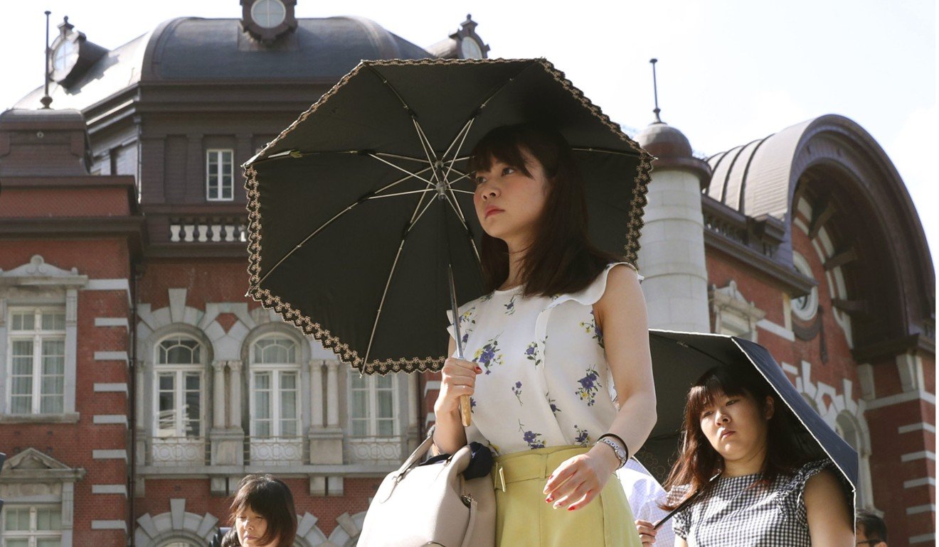 Women walk with umbrellas in front of JR Tokyo Station, as an extreme heatwave hits Japan. Photo: Kyodo