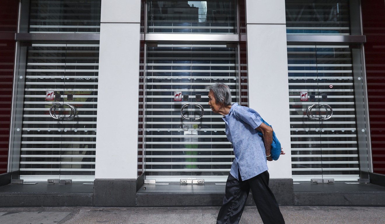 An elderly woman walks past the HSBC building in Mong Kok. Photo: Nora Tam