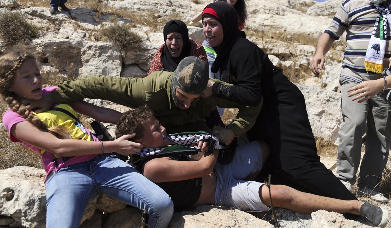 In this August 28, 2015 file photo, Nariman Tamimi and her daughter Ahed try to free her son Mohammed from an Israeli soldier during a protest near the West Bank village of Nabi Saleh. Photo: AP