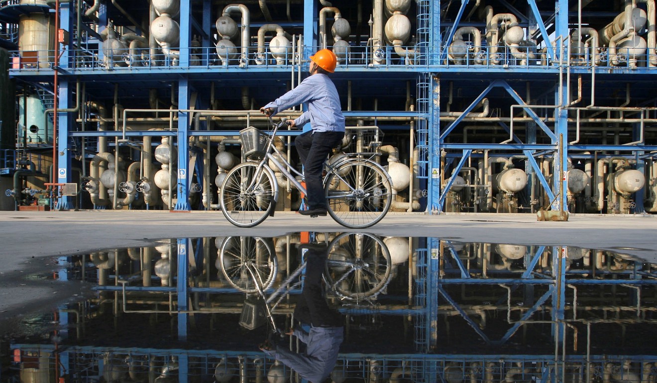 An engineer on a bicycle checks pipelines at an oil refinery in Lanzhou, Gansu province. Sinochem Energy says it is expanding its annual refining capacity from 12 million to 15 million tonnes. Photo: Reuters