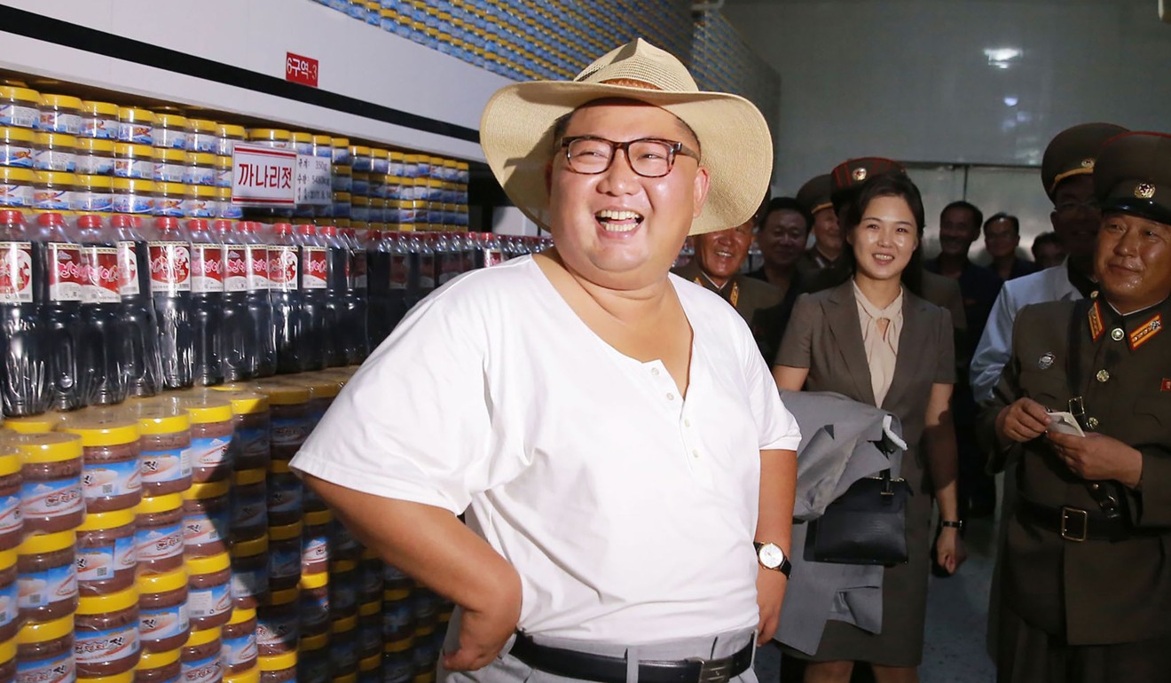 Wearing his trademark smile, Kim Jong-un tours the Kumsanpho Fish Pickling Factory with his wife, Ri Sol-ju, holding his suit jacket in the background, in an undated picture released by North Korea's official Korean Central News Agency. Photo: AFP/KCNA via KNS