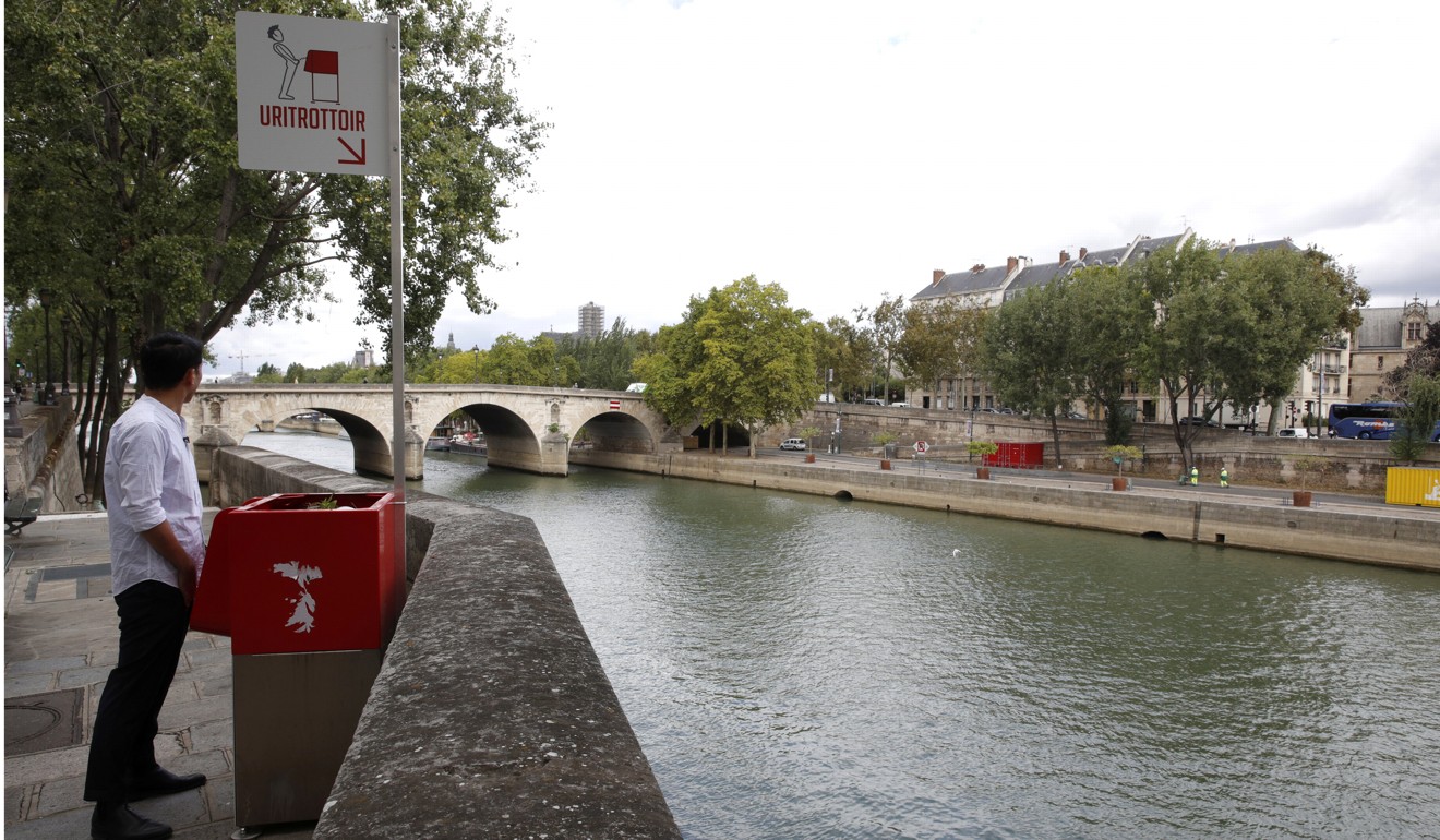 A journalist pretends to use one of the bright red, eco-friendly urinals. Photo: Reuters