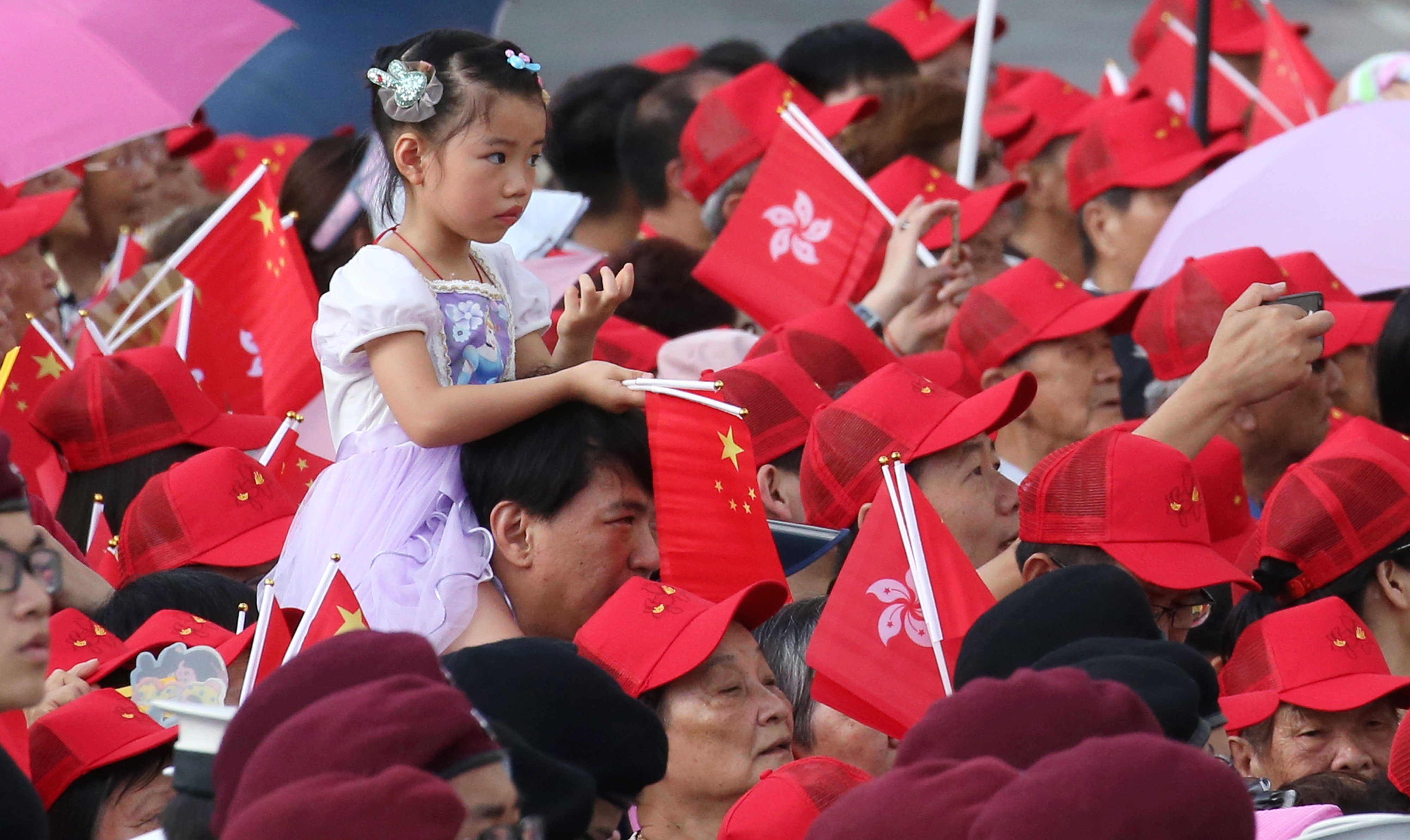 A child is carried during the flag-raising ceremony at the Golden Bauhinia Square in Wan Chai to mark the 21st anniversary of the establishment of the Hong Kong Special Administrative Region. Photo: David Wong