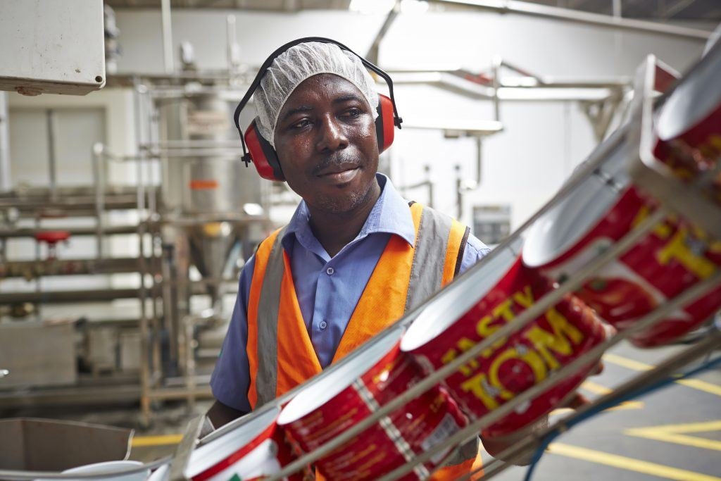 A machine minder is kept busy at the Tasty-Tom tomato cannery at Olam’s Nutrifoods Ghana Limited, in Tema.