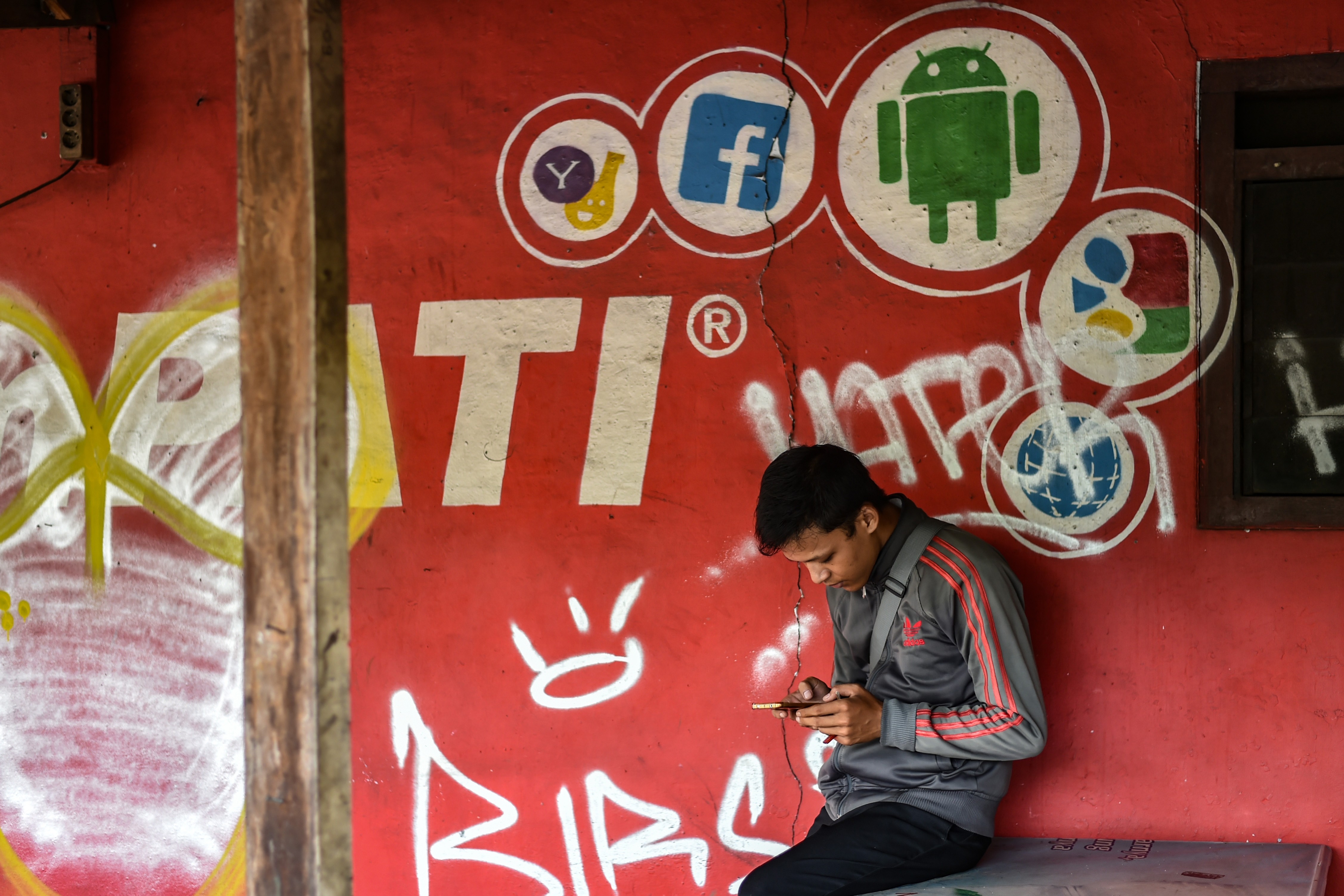 A man uses his phone in front of a mobile service provider’s advertisement in Jakarta, Indonesia, in March. Governments in Southeast Asia have ambitious road maps to tap the benefits of the digital economy but have also rushed to regulate it. Photo: AFP