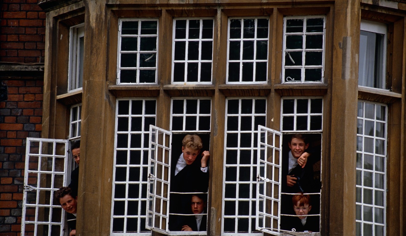 Boys lean out of the windows of their room at Eton College in Berkshire, outside London. Photo: Alamy