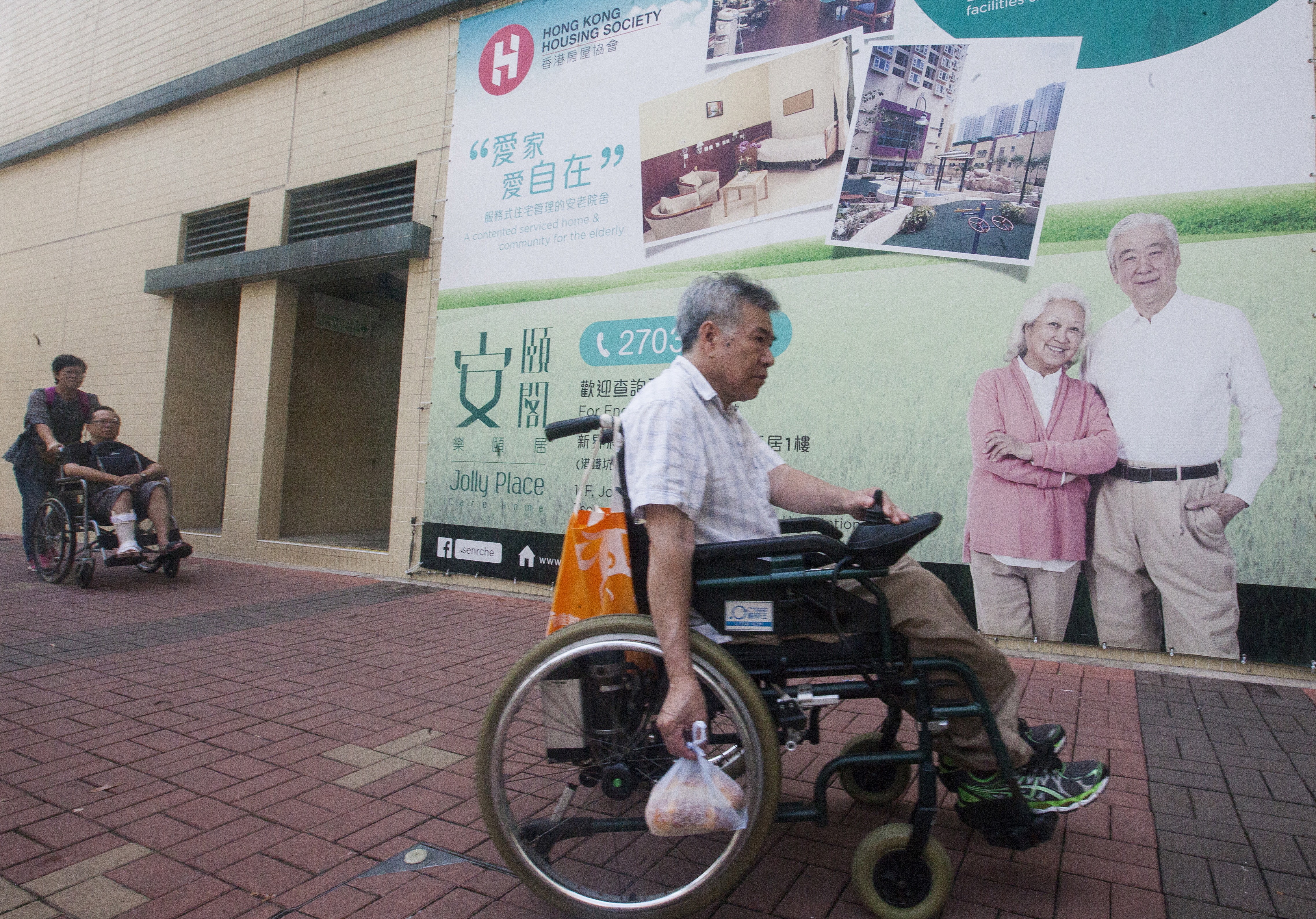 An elderly person passes a billboard advert for a care home near a public housing estate in Tseung Kwan O, on July 6. Hong Kong is facing a “silver tsunami” as the population ages. Photo: EPA-EFE