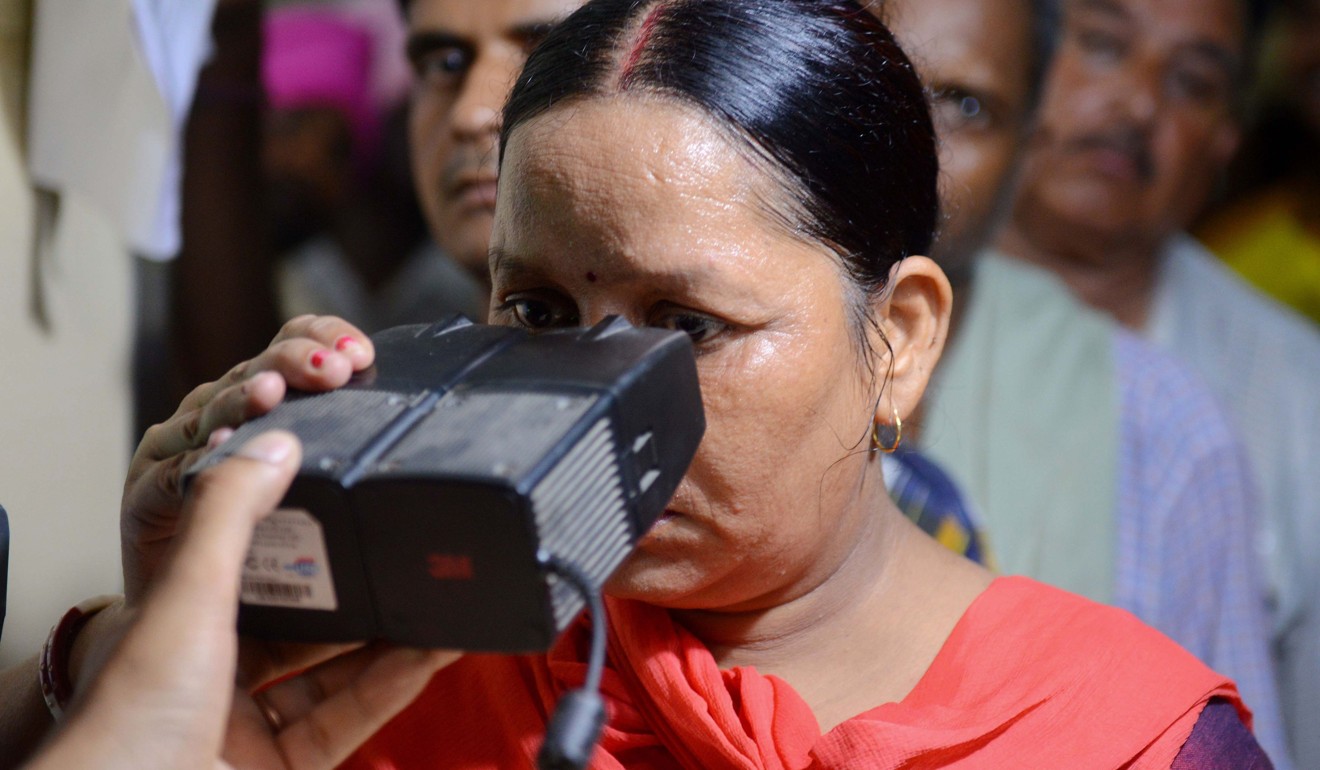 A woman looking through an optical biometric reader, which scans iris patterns, while registration for an Aadhaar card in Amritsar, India. Photo: AFP