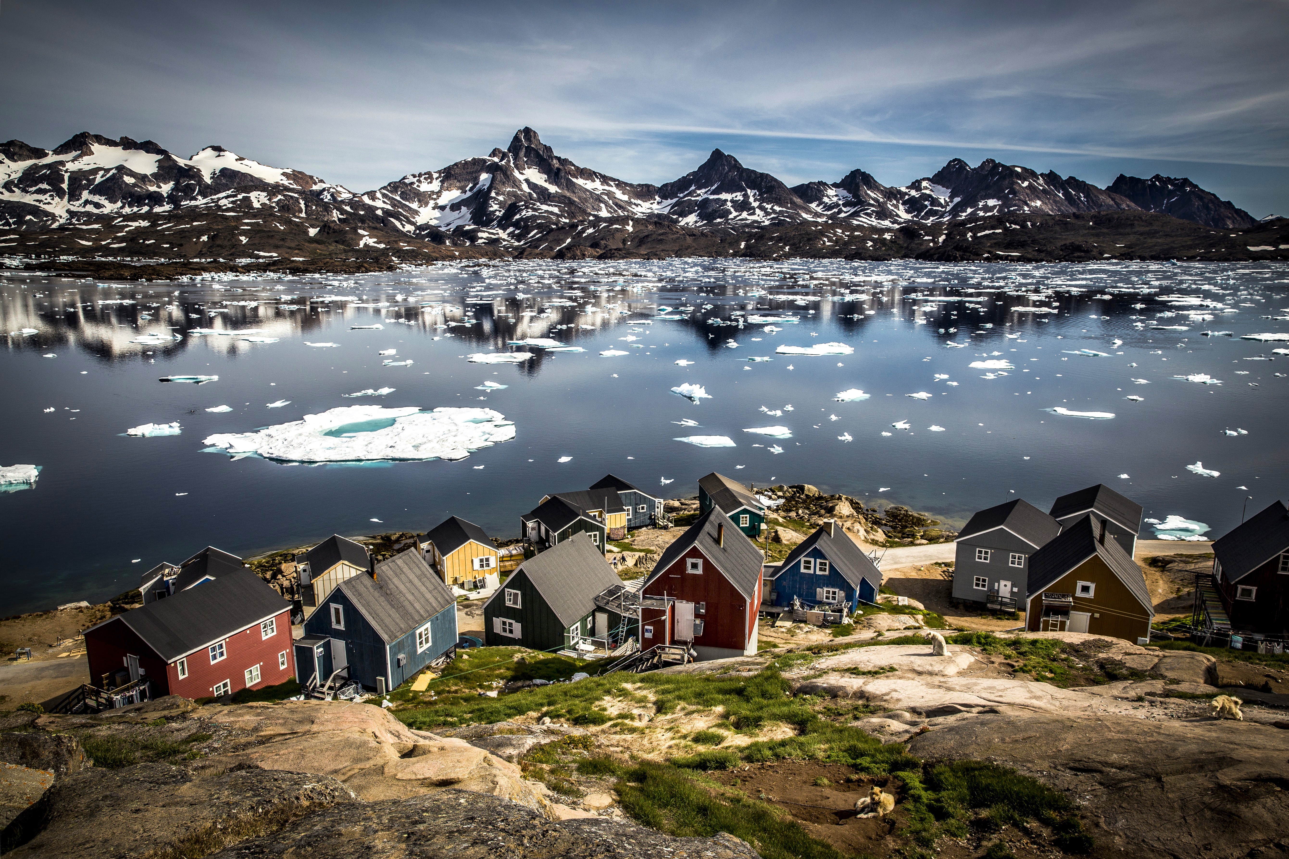 Houses in Tasiilaq at the edge of Kong Oskars Havn with the mountain Polheim in the background.