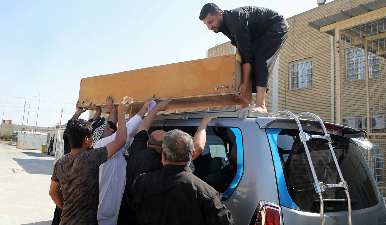 Family members of slain activist Soad al-Ali load her coffin onto a vehicle before burial, in Basra. Photo: AP